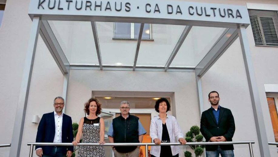 Eine Gruppe von Menschen steht unter einem Schild mit der Aufschrift „Kulturhaus Ca da Cultura“