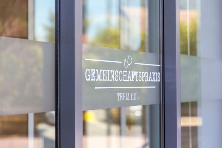 Eine Glastür mit einem Schild darauf, auf dem steht „Gemeinschaftspraxis“