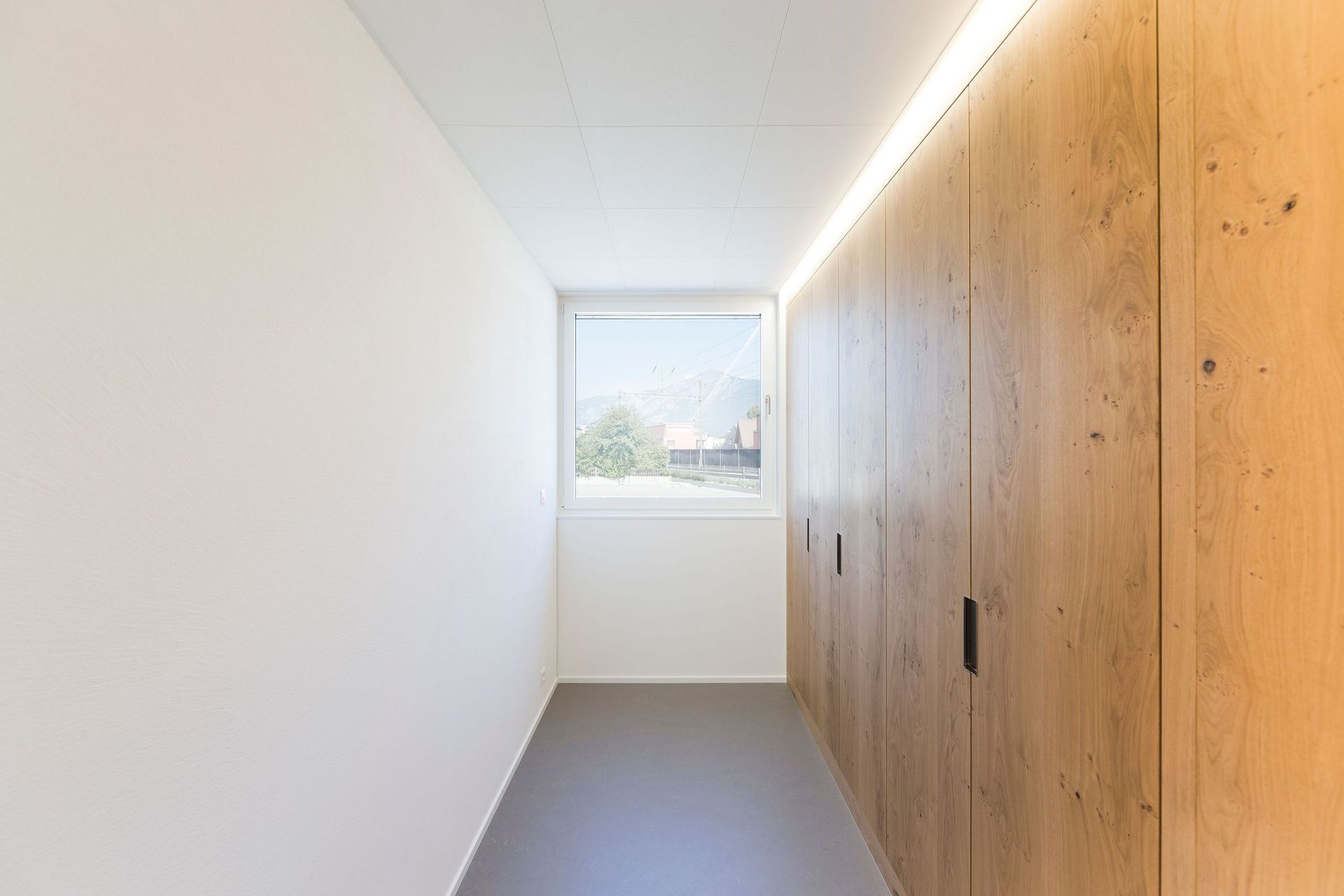 Ein langer Flur mit Holzwänden und einem Fenster.