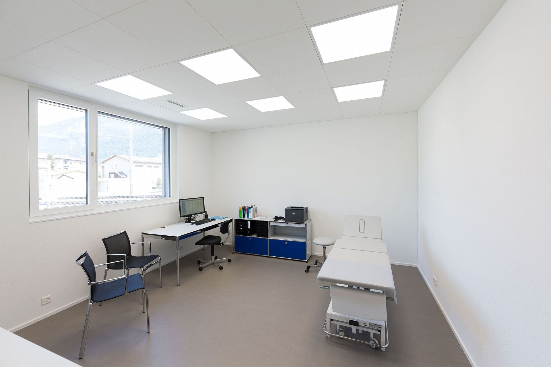 Eine Arztpraxis mit einem Schreibtisch, Stühlen und einem Bett.