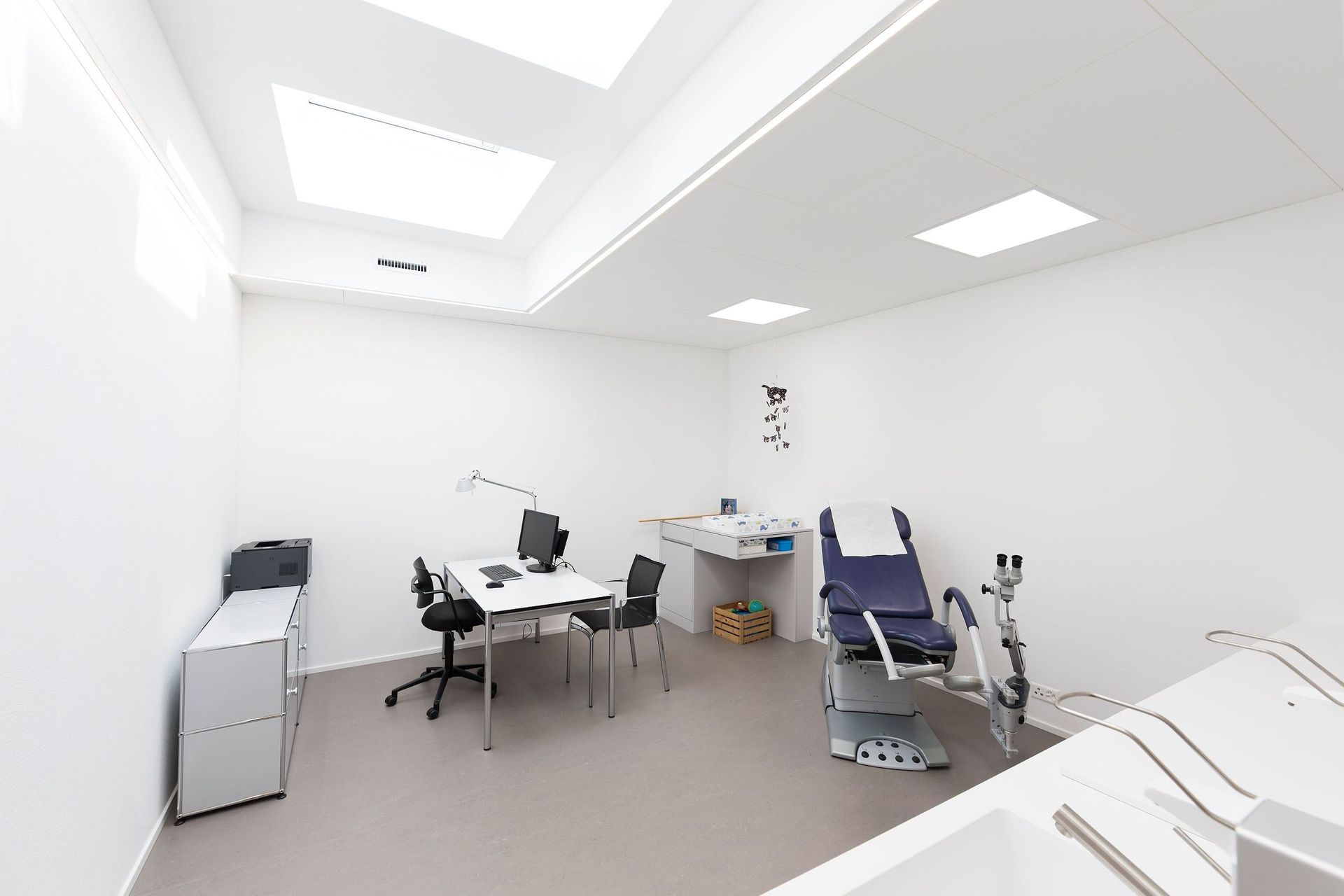 Eine Arztpraxis mit gynäkologischem Stuhl und Schreibtisch.