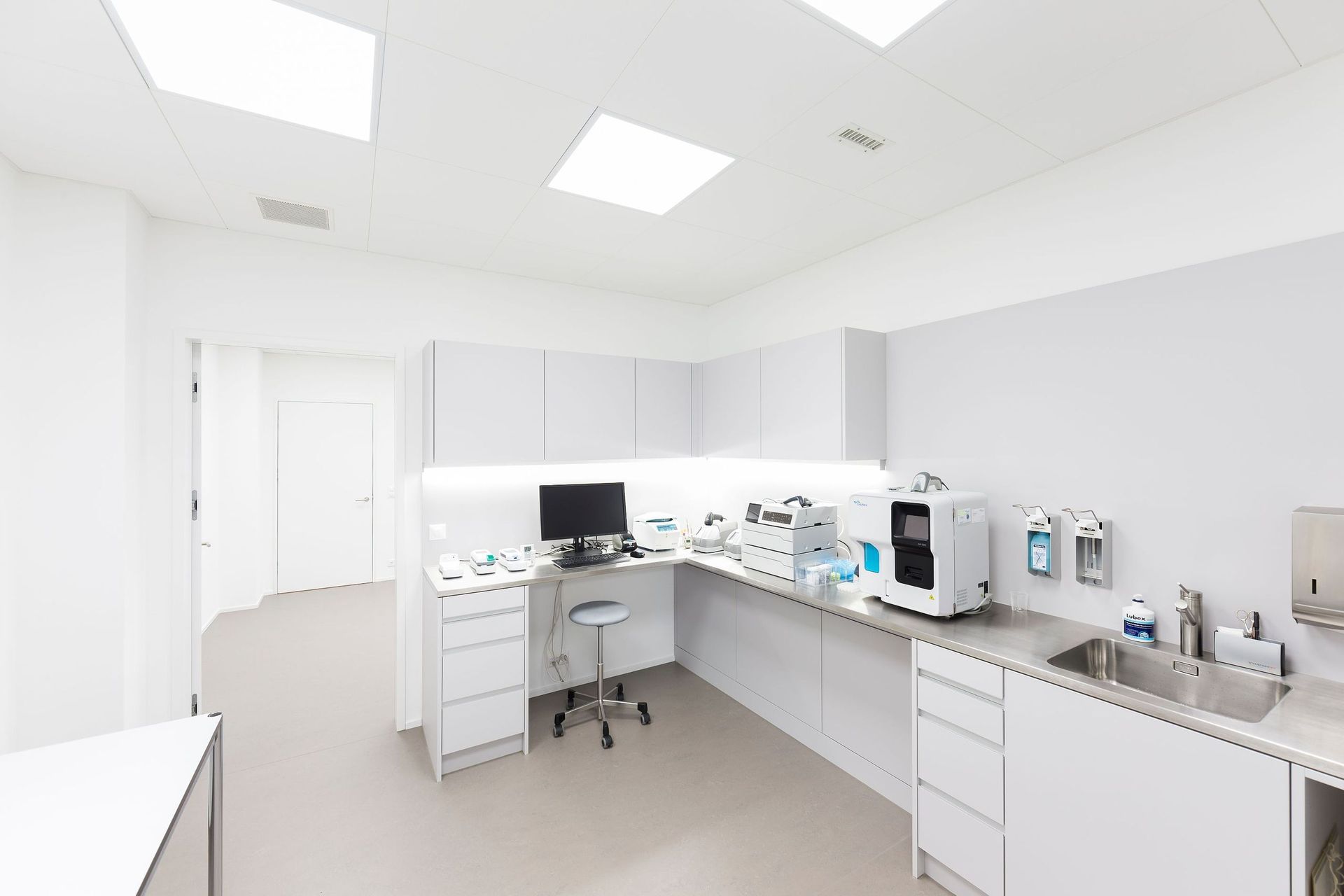 Eine Zahnarztpraxis mit einem Computer auf einem Schreibtisch und einem Waschbecken.