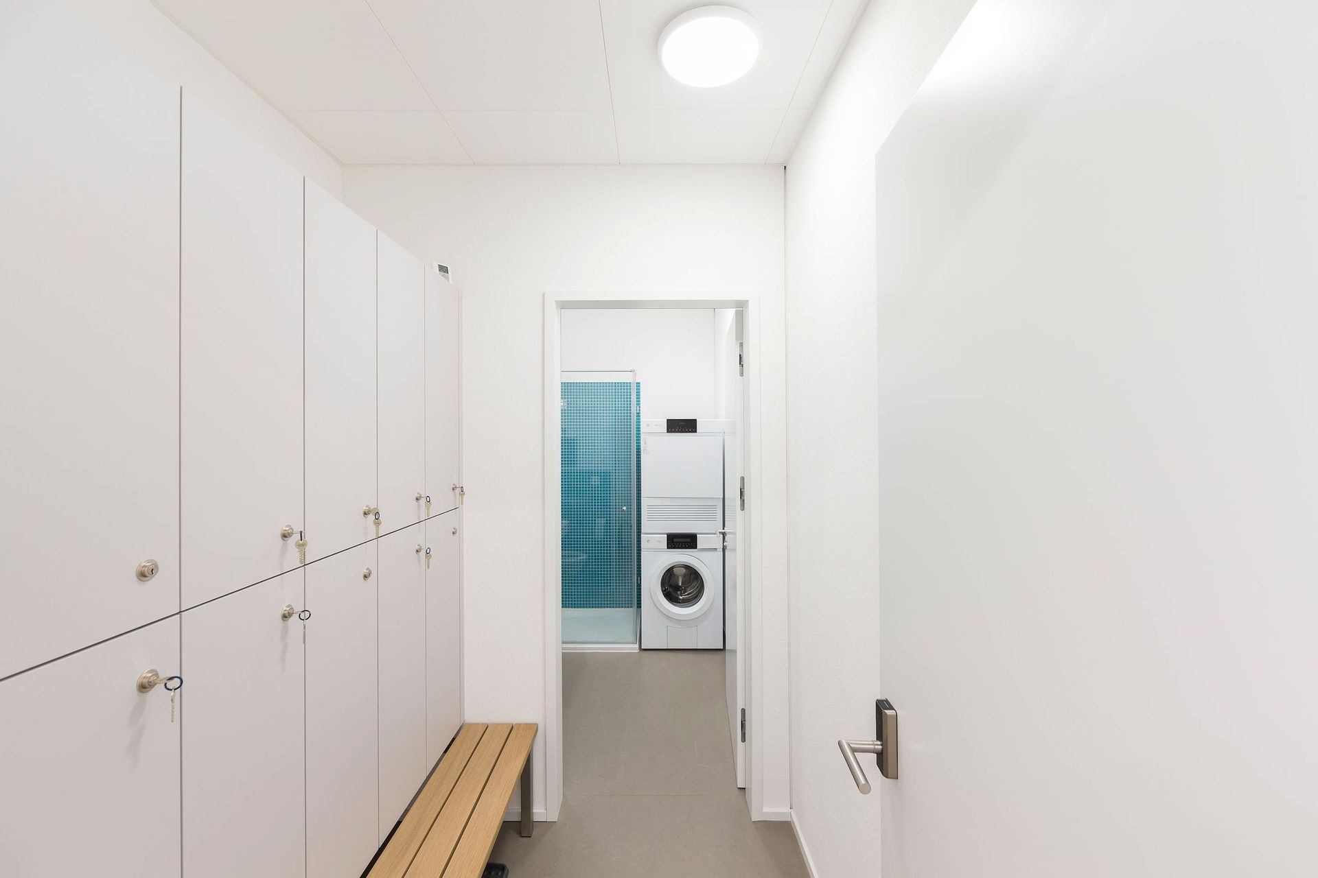 Ein Umkleideraum mit Bank sowie Waschmaschine und Trockner.