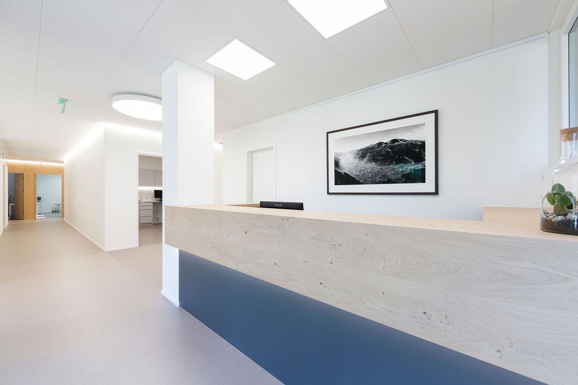 Ein Empfangstresen in einem Krankenhaus mit einem Bild darüber an der Wand.