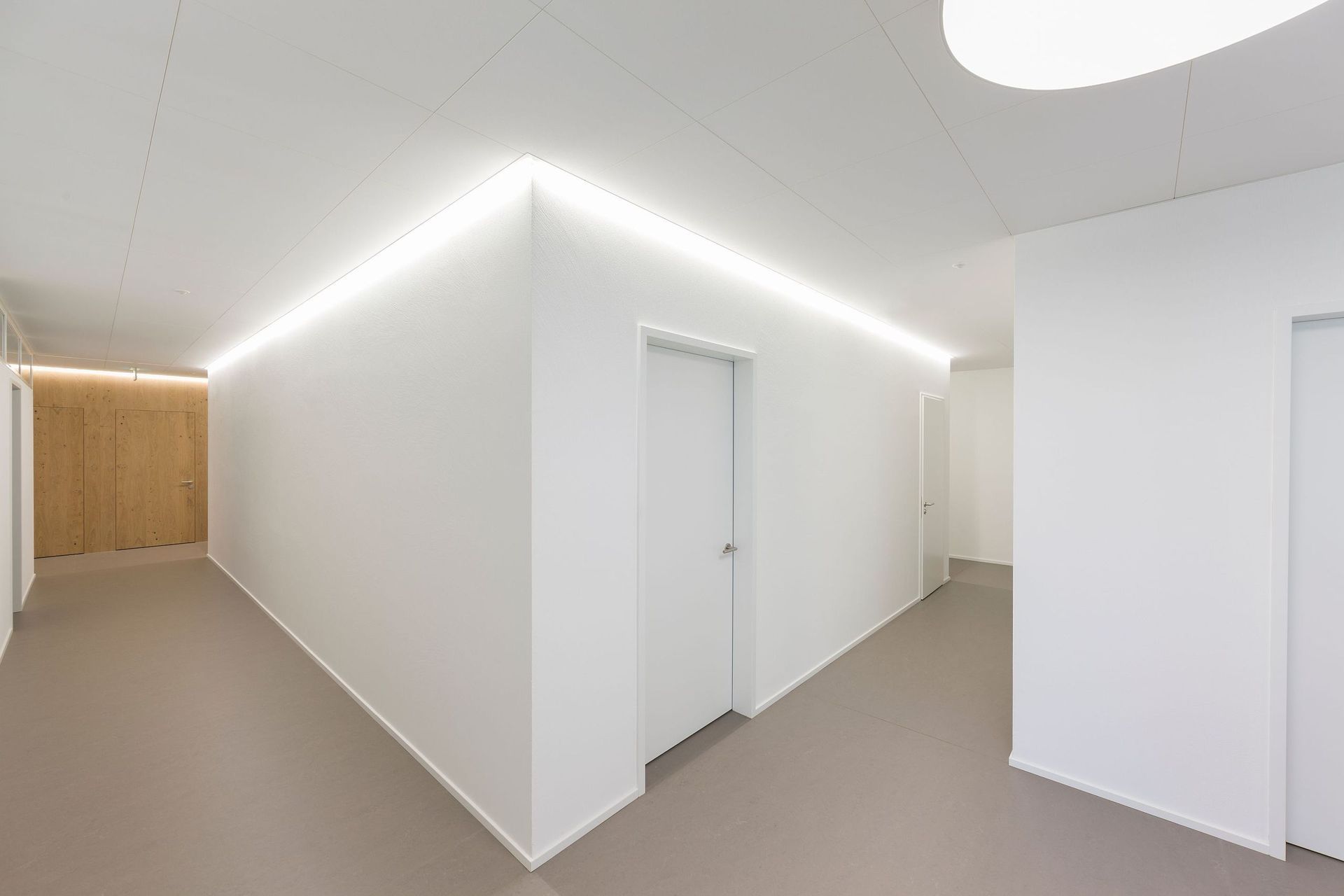 Ein langer Flur mit weißen Wänden und einer Lampe an der Decke.