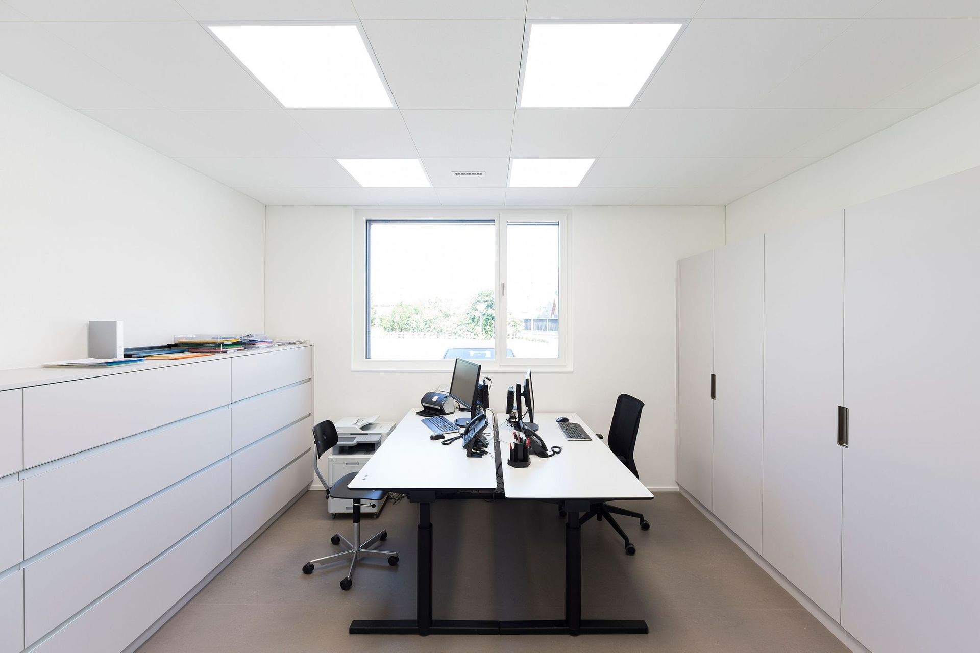 Ein kleines Büro mit zwei Schreibtischen und einem Fenster.