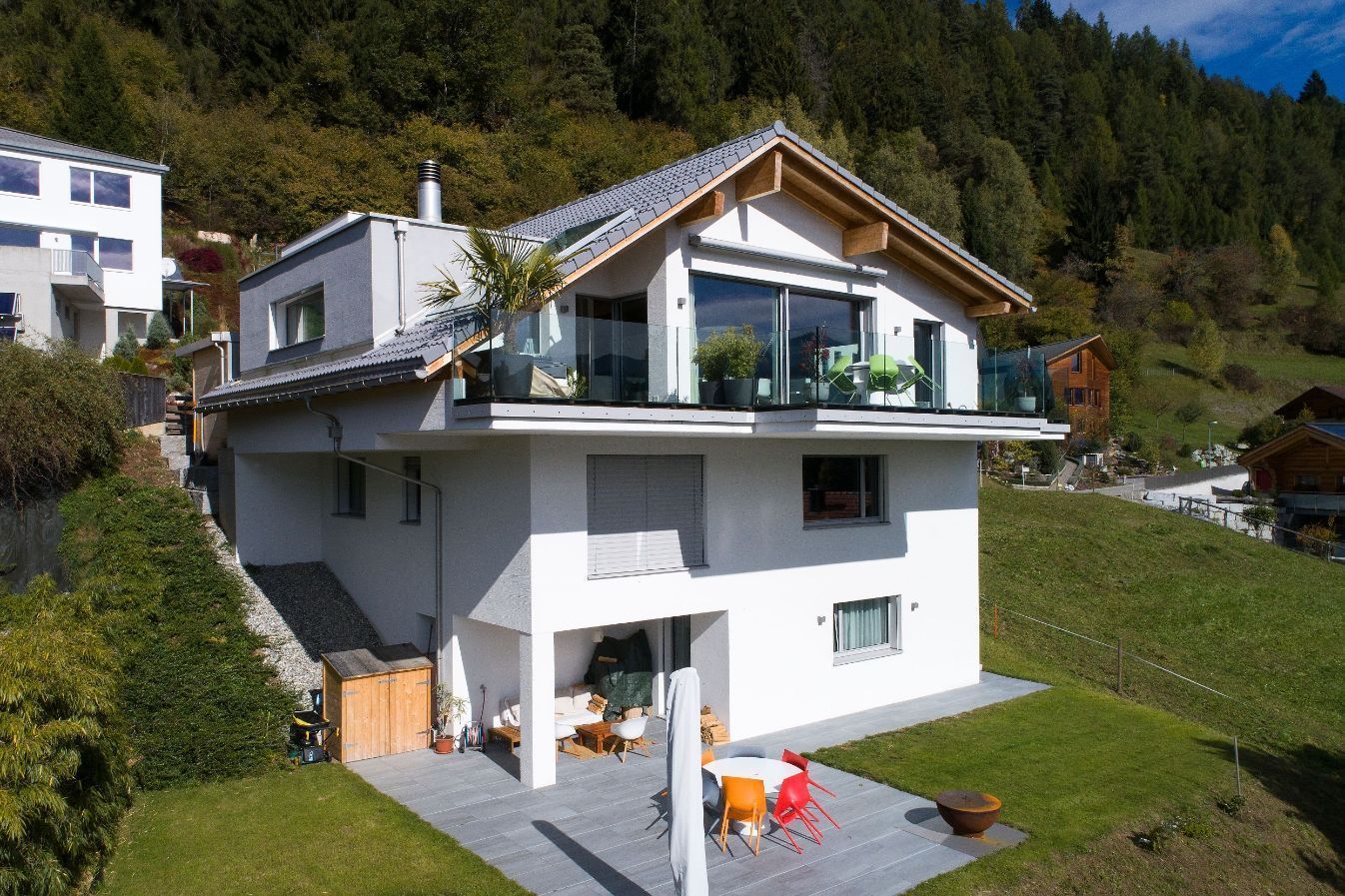 Ein großes weißes Haus steht auf einem Hügel, umgeben von Bäumen.