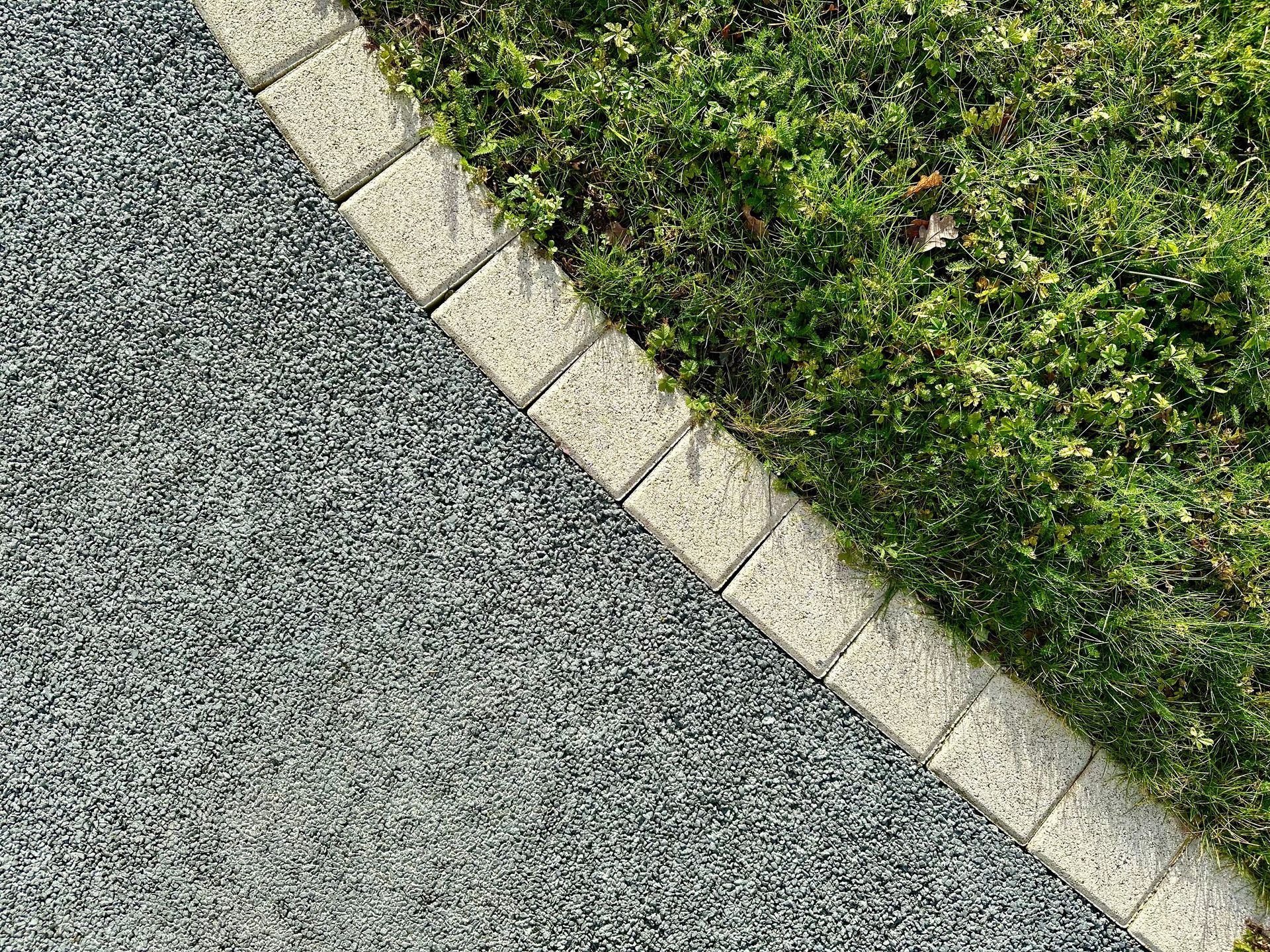 Chemin de gravier bordé de pierres claires et d'une haie verte