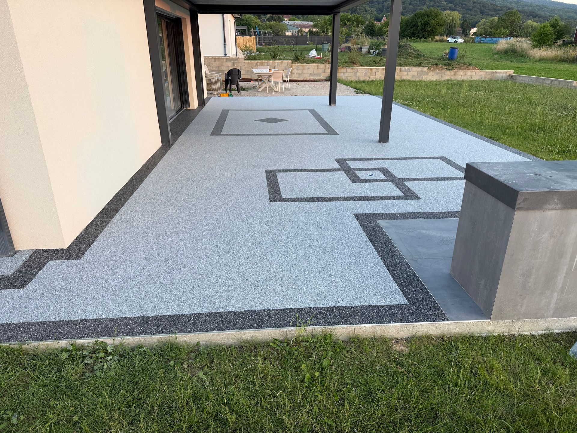 Terrasse arrière avec chemin de pierre, pelouse verte et sièges extérieurs près des haies