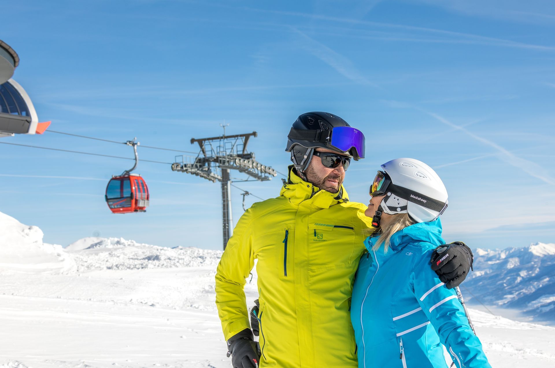 Ein Mann und eine Frau stehen nebeneinander auf dem Gipfel eines schneebedeckten Berges.