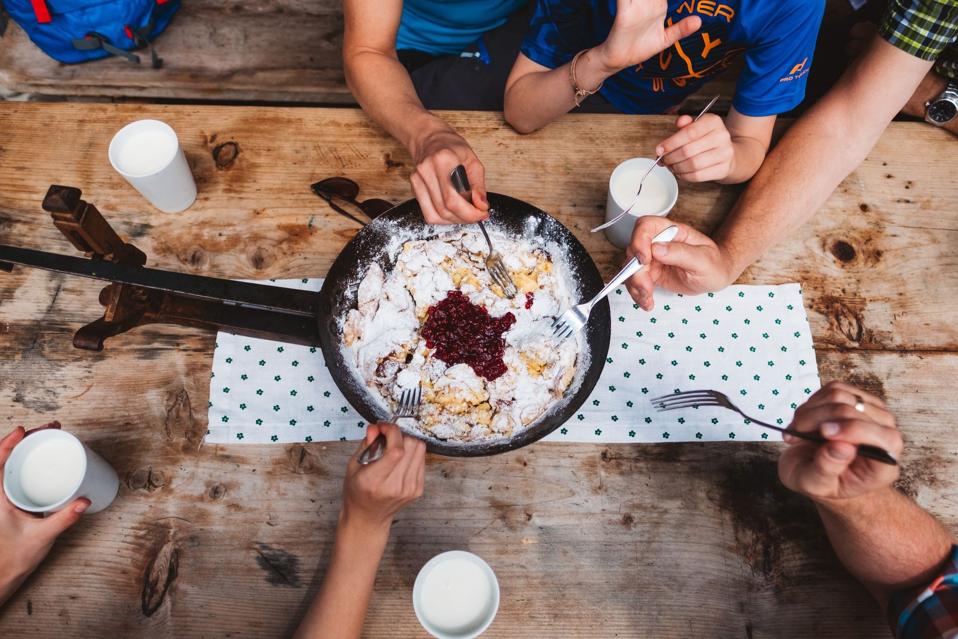 Eine Gruppe Leute sitzt an einem Tisch und isst Essen aus einer Pfanne.