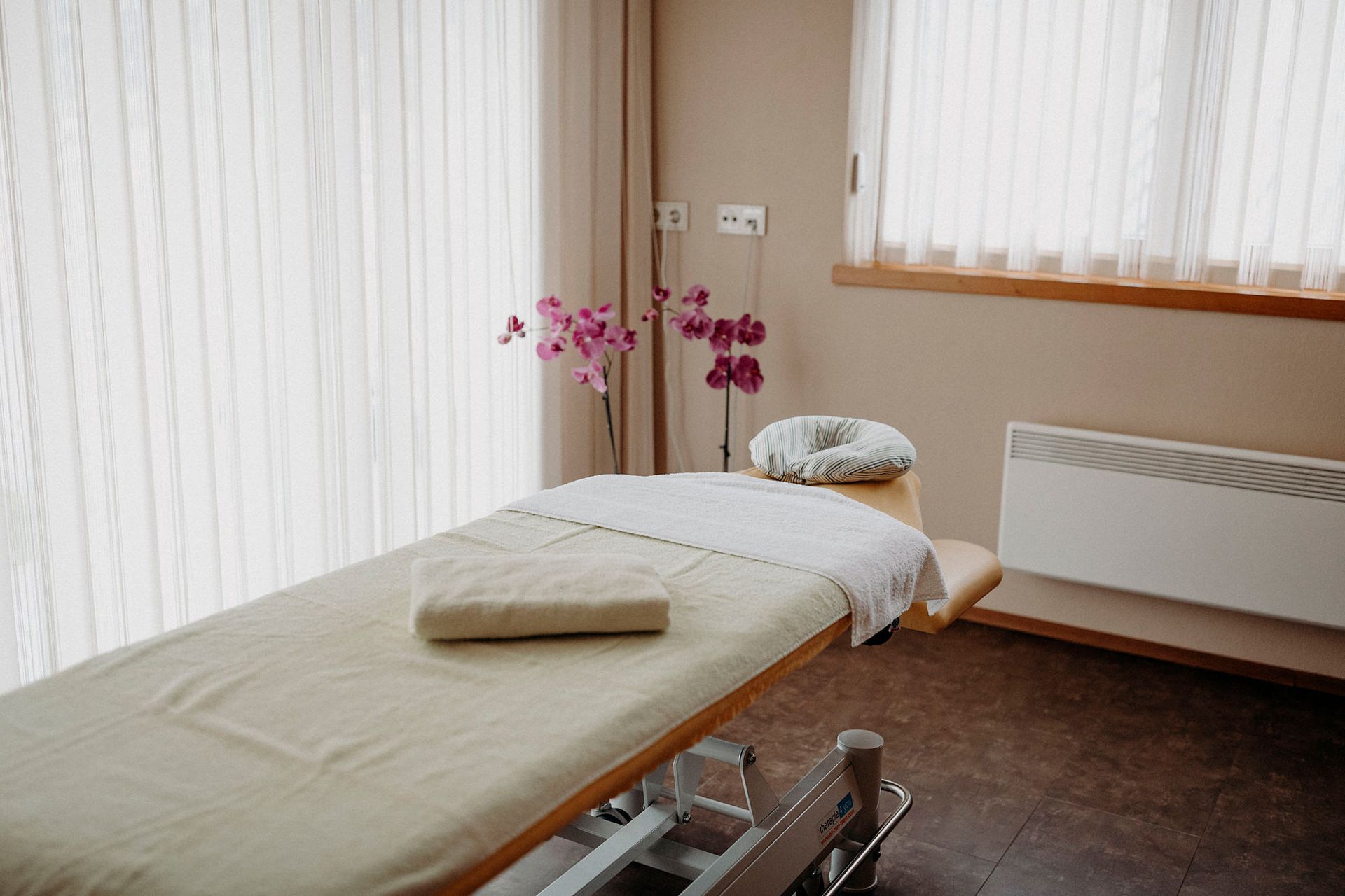 In einem Raum neben einem Fenster steht eine Massageliege.