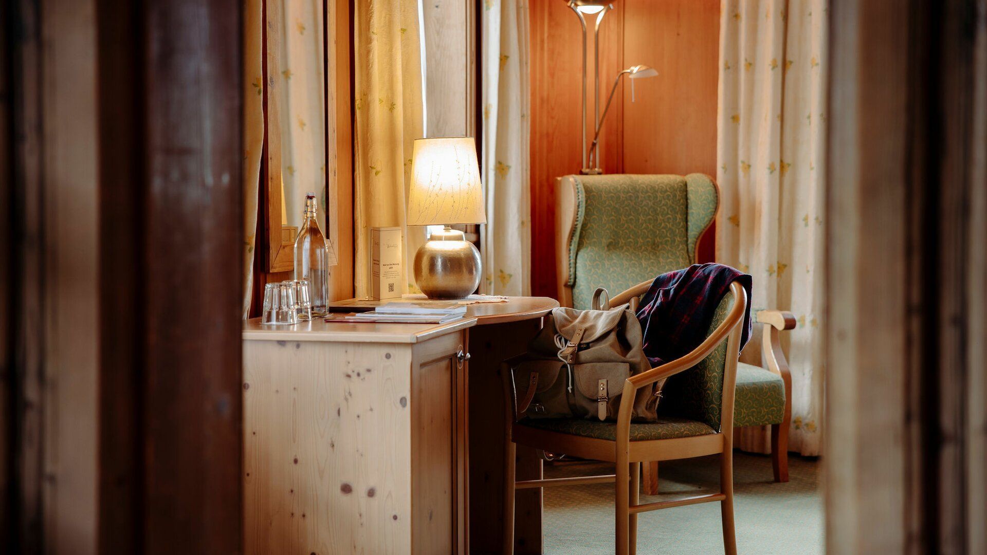 Ein Hotelzimmer mit Schreibtisch, Stuhl und Lampe.