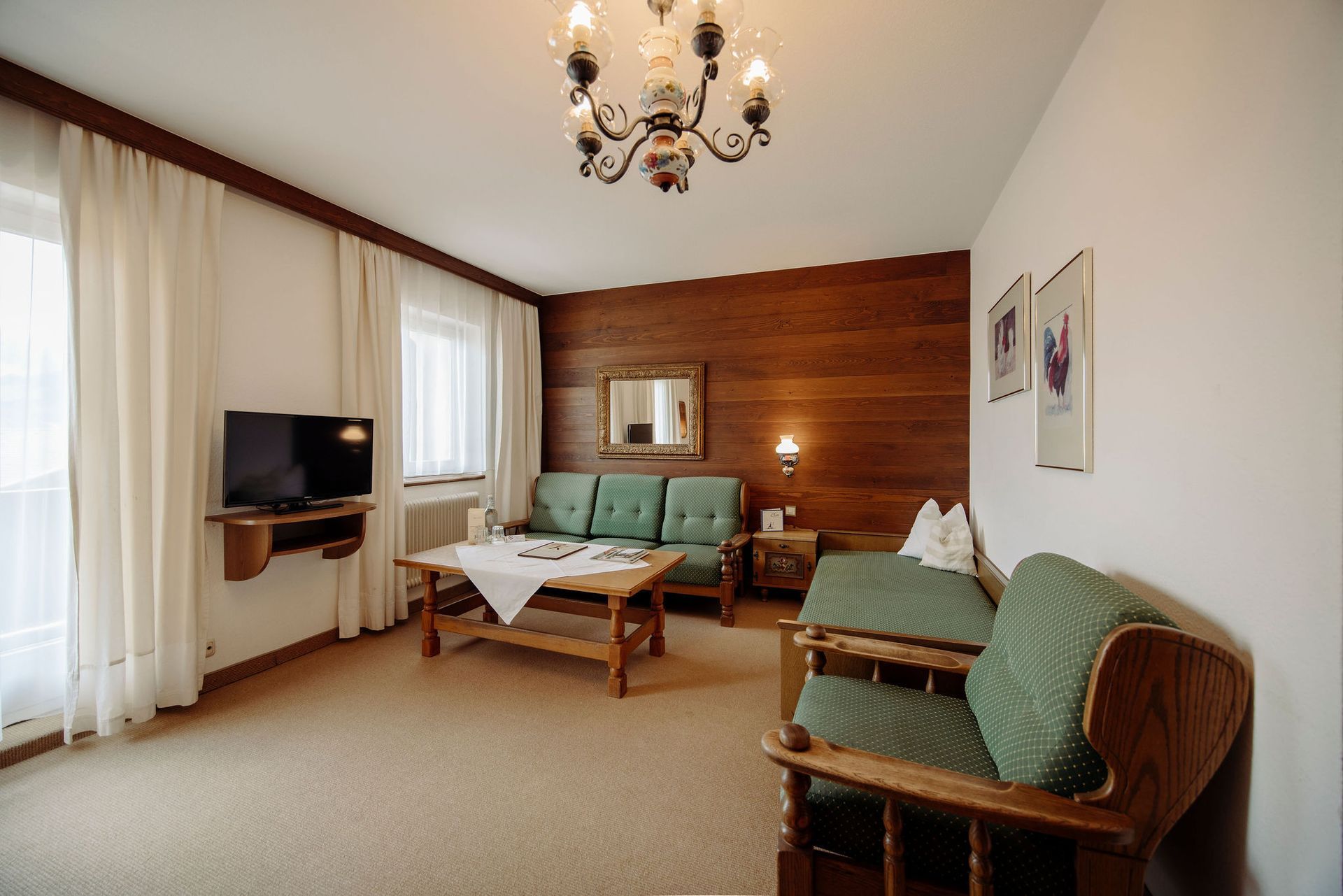 Ein Wohnzimmer mit Couch, Sessel, Tisch und Fernseher.