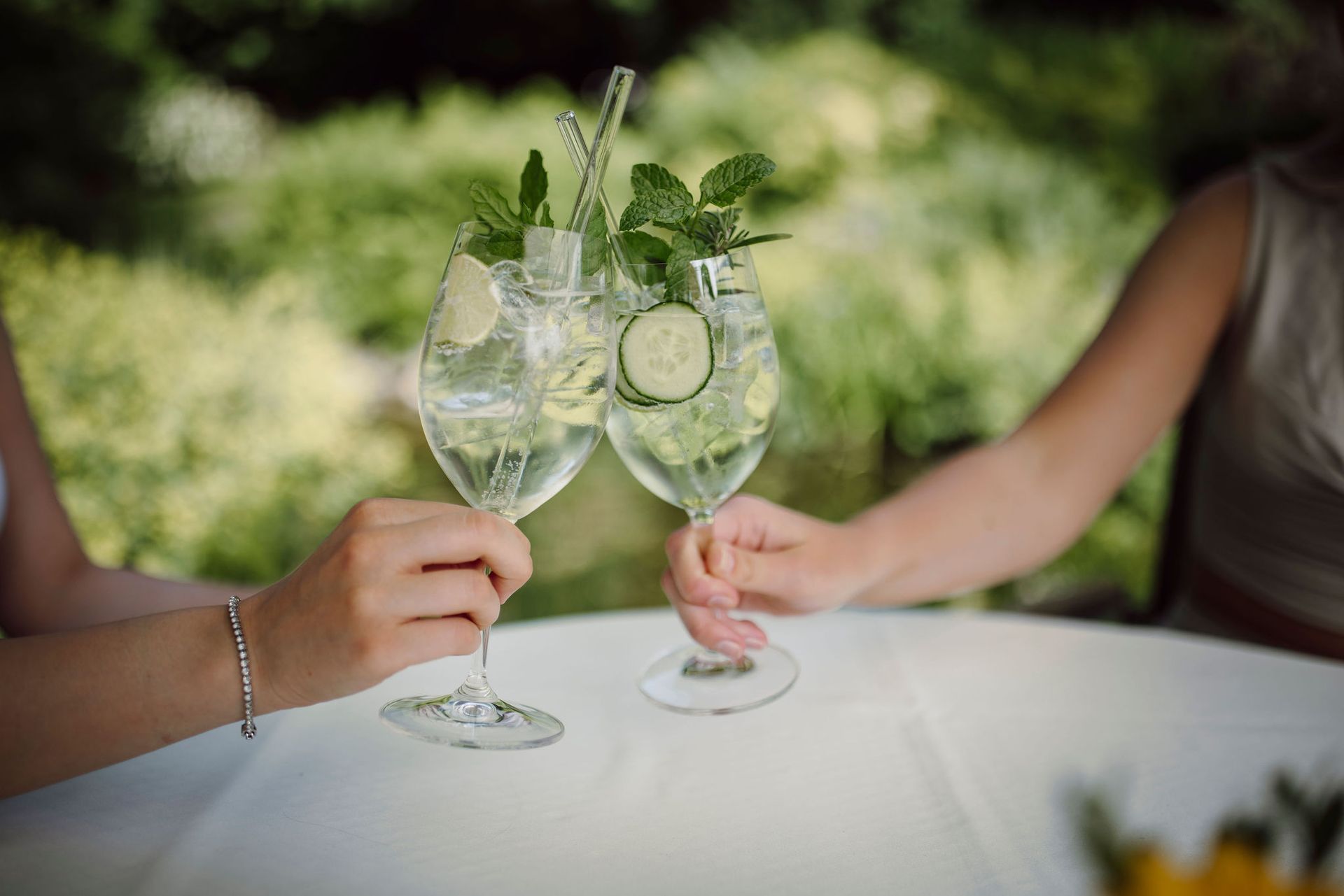 Zwei Frauen sitzen an einem Tisch und halten Weingläser mit Getränken darin.