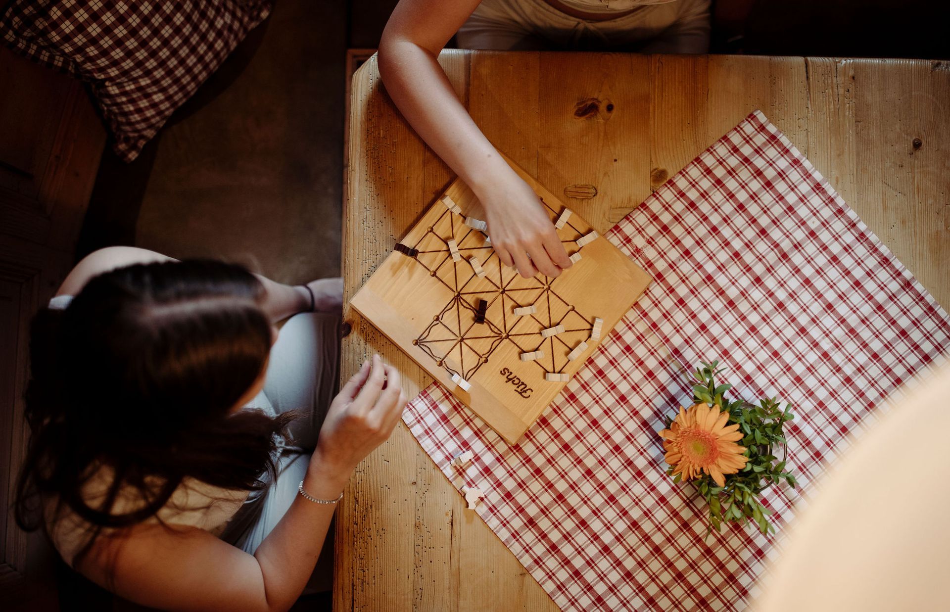 Eine Frau und ein Kind spielen ein Spiel auf einem Holztisch.