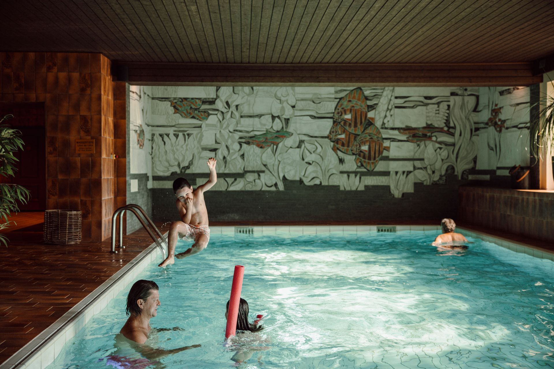 Eine Gruppe von Menschen schwimmt in einem Hallenbad.