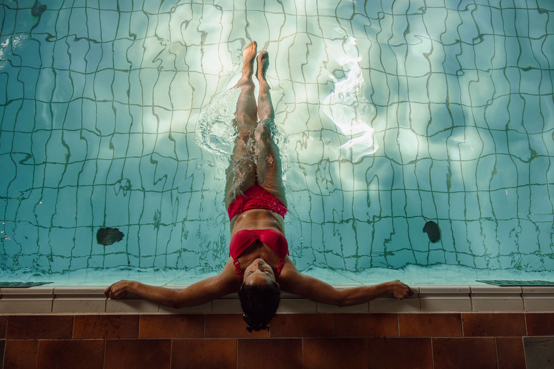 Eine Frau in einem roten Bikini liegt auf ihrem Rücken in einem Schwimmbecken.