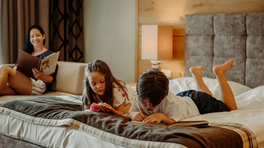Eine Familie liegt in einem Hotelzimmer auf einem Bett