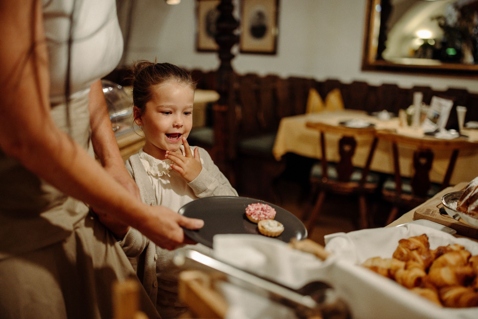 In einem Restaurant serviert eine Frau einem kleinen Mädchen einen Teller Kekse.