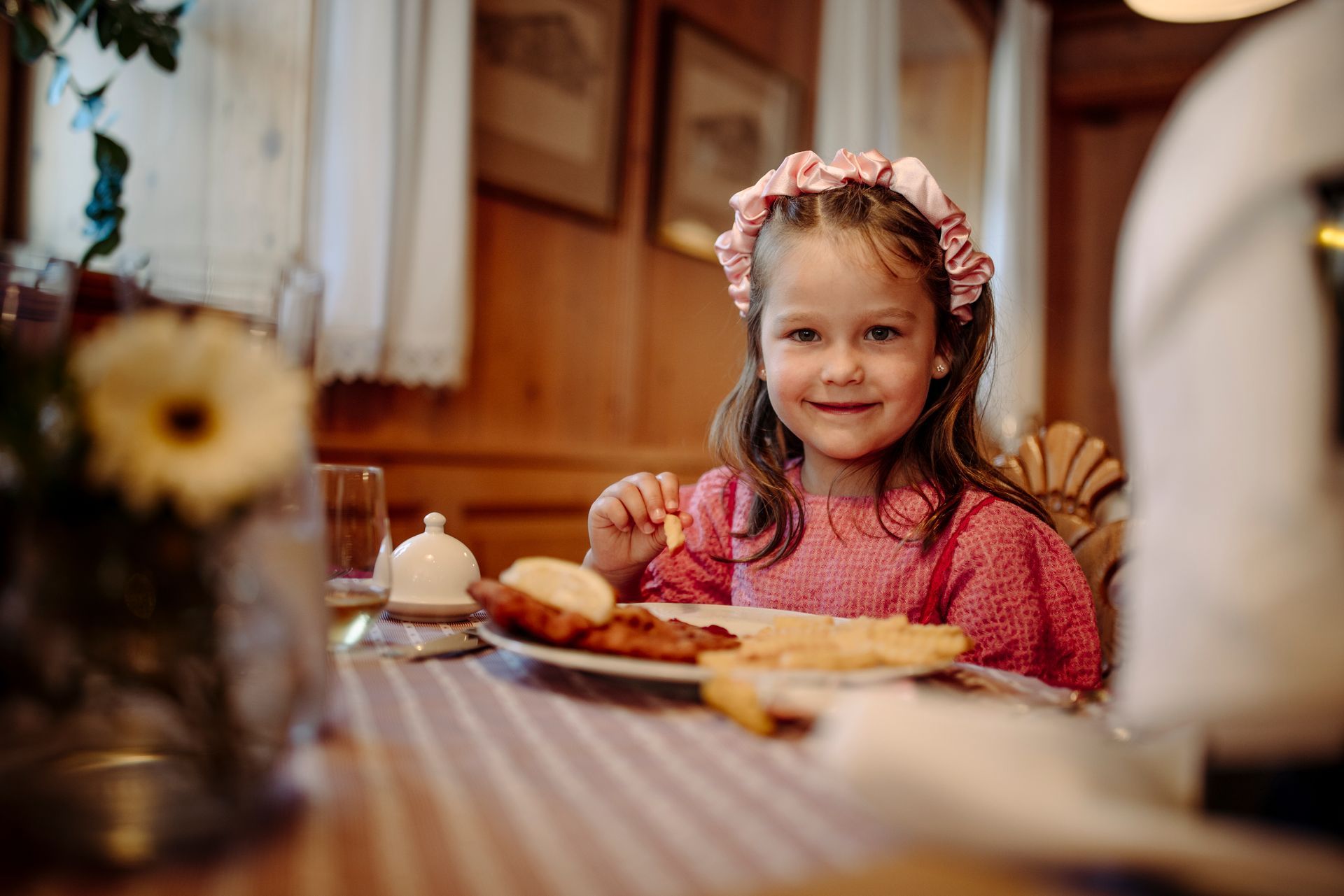 Ein kleines Mädchen sitzt an einem Tisch und isst.