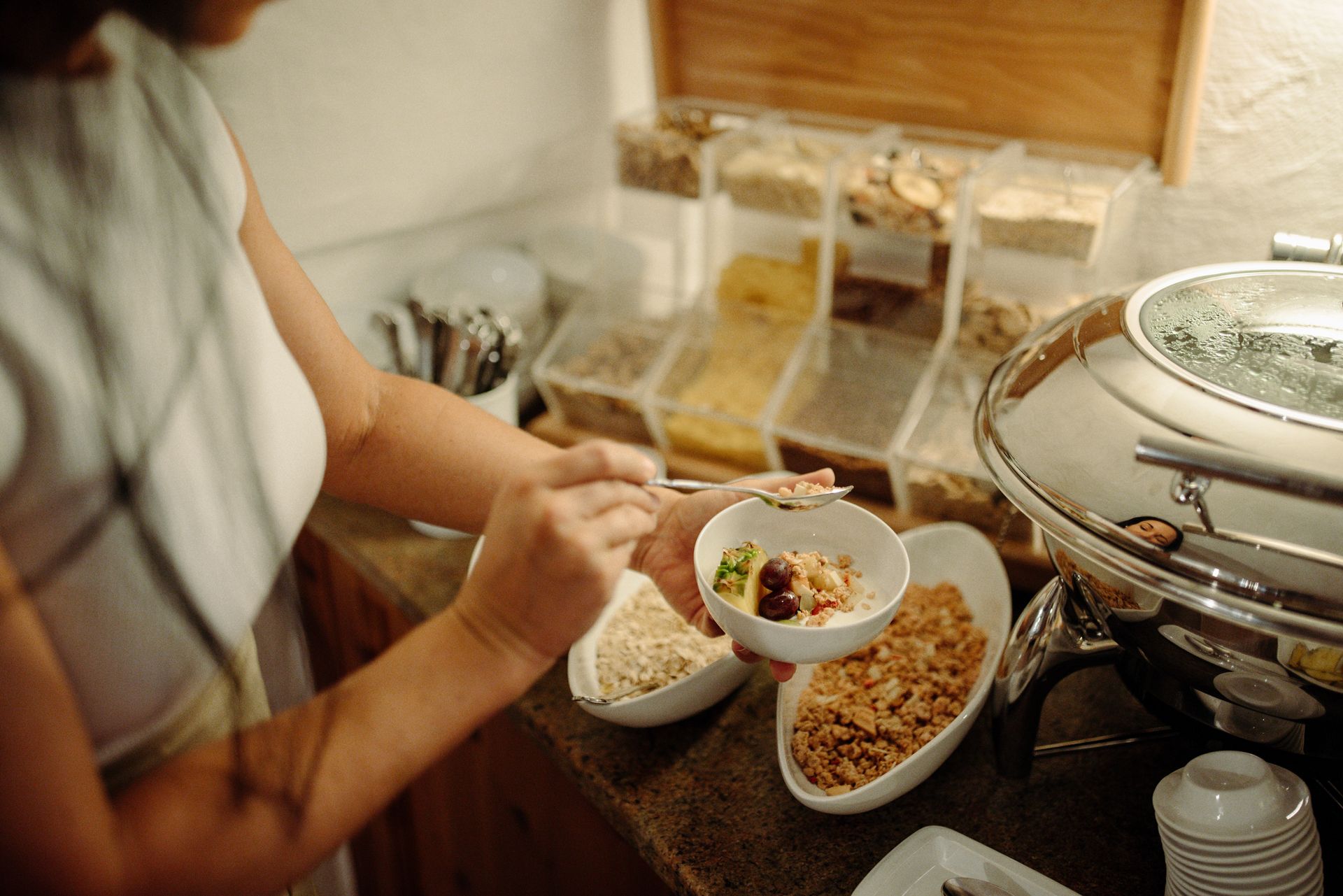 Eine Frau nimmt eine SchĂźssel mit Essen von einem Buffet.