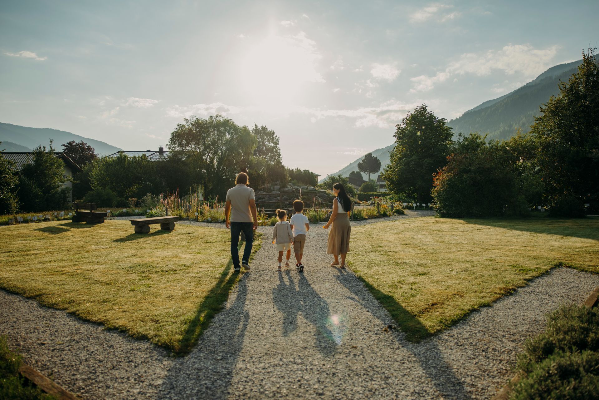 Eine Familie geht Hand in Hand einen Weg in einem Park entlang.