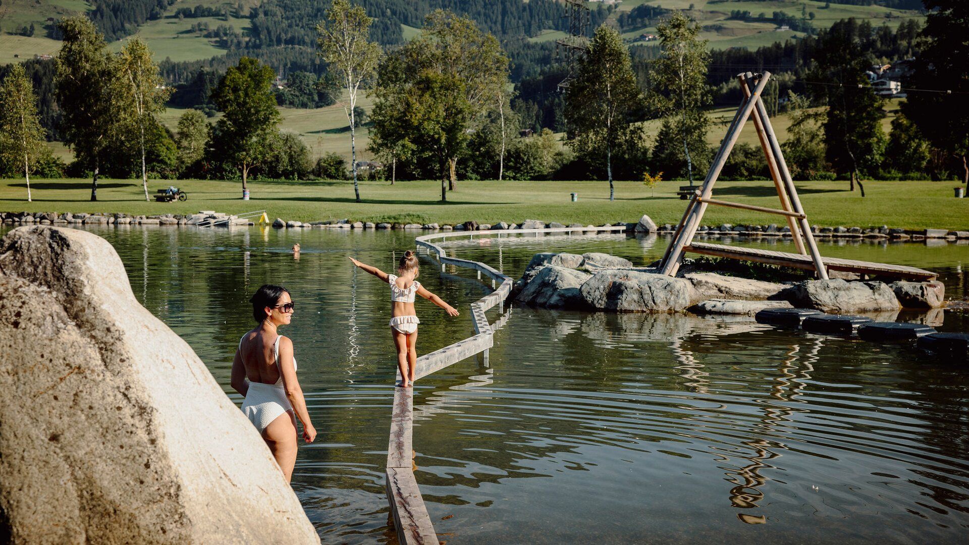 Eine Frau und ein Kind stehen auf einem Baumstamm im Wasser.