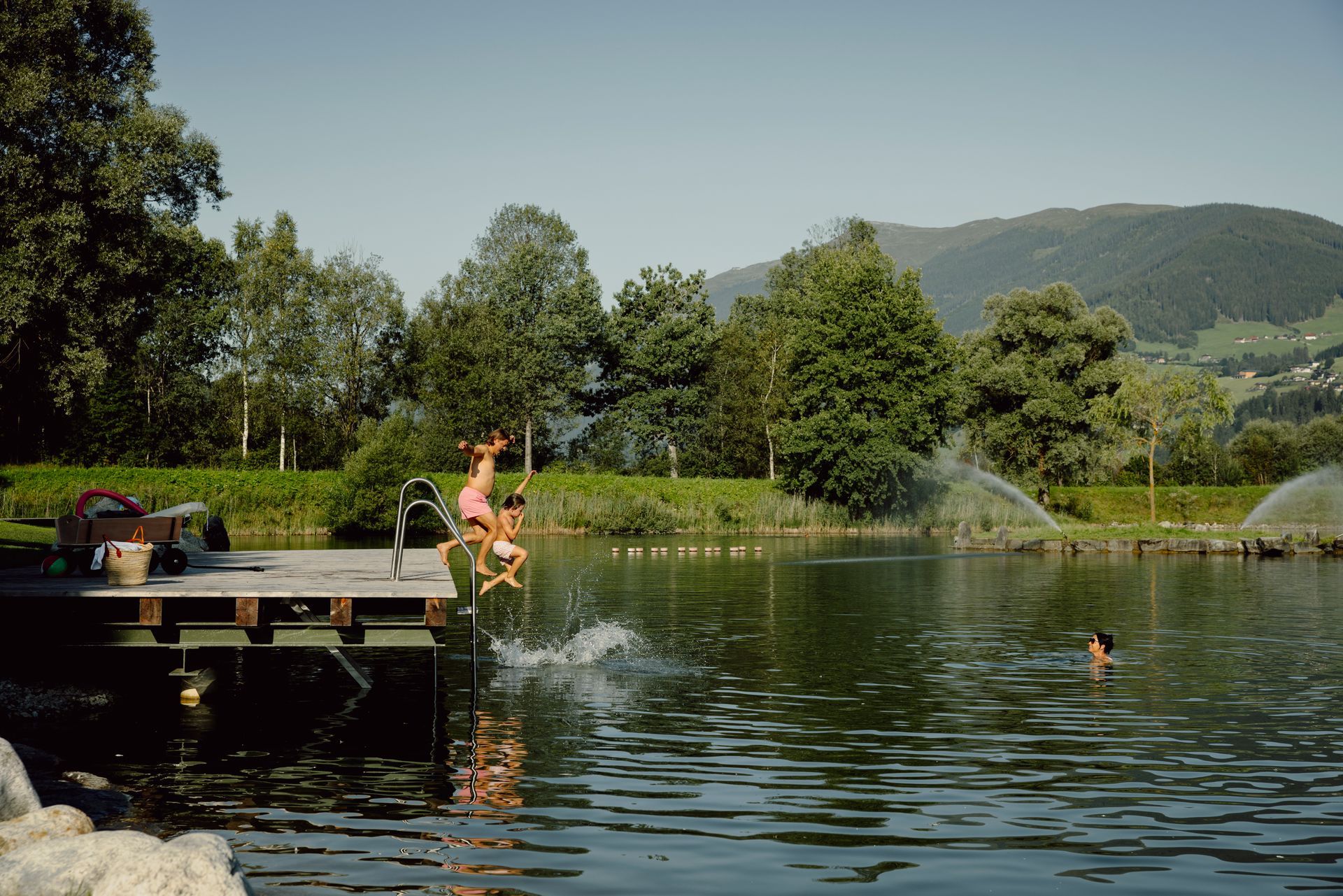 Eine Person springt von einem Steg in einen See.