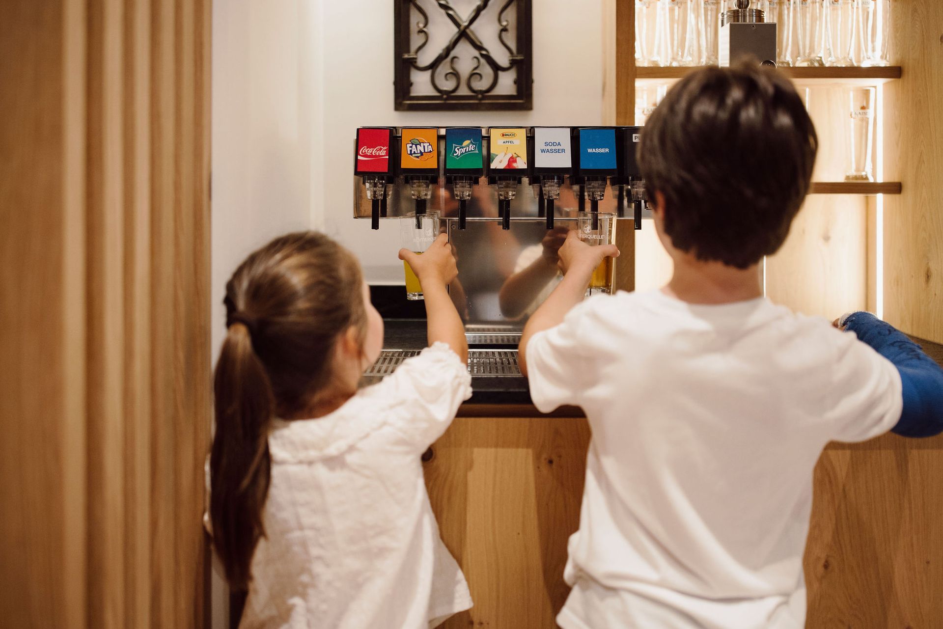 Ein Junge und ein Mädchen spielen mit einem Getränkeautomaten.