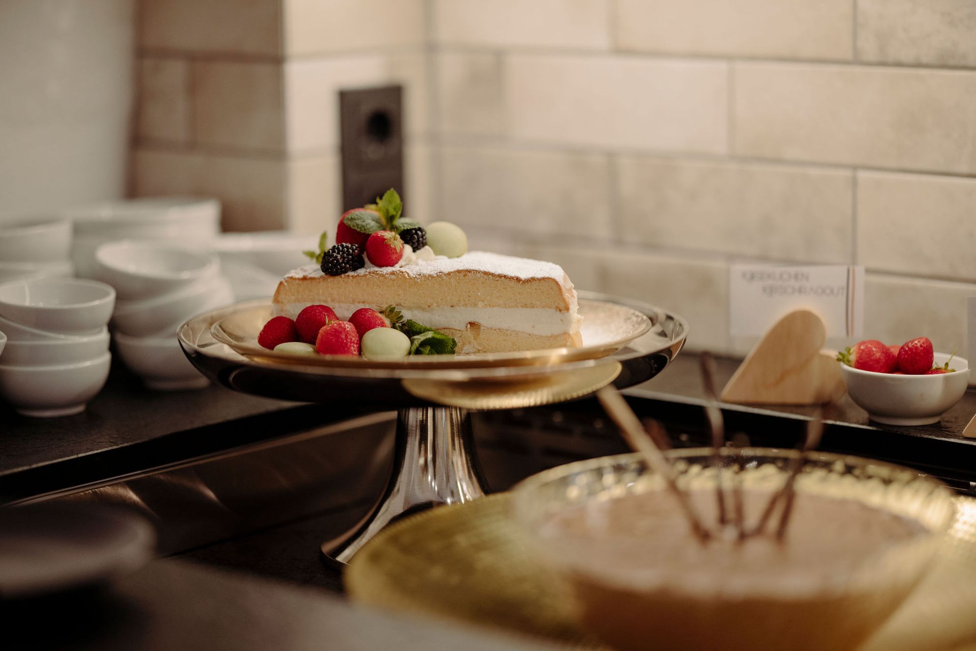 Ein Stück Kuchen mit Beeren darauf liegt auf einem Teller auf einem Tisch.