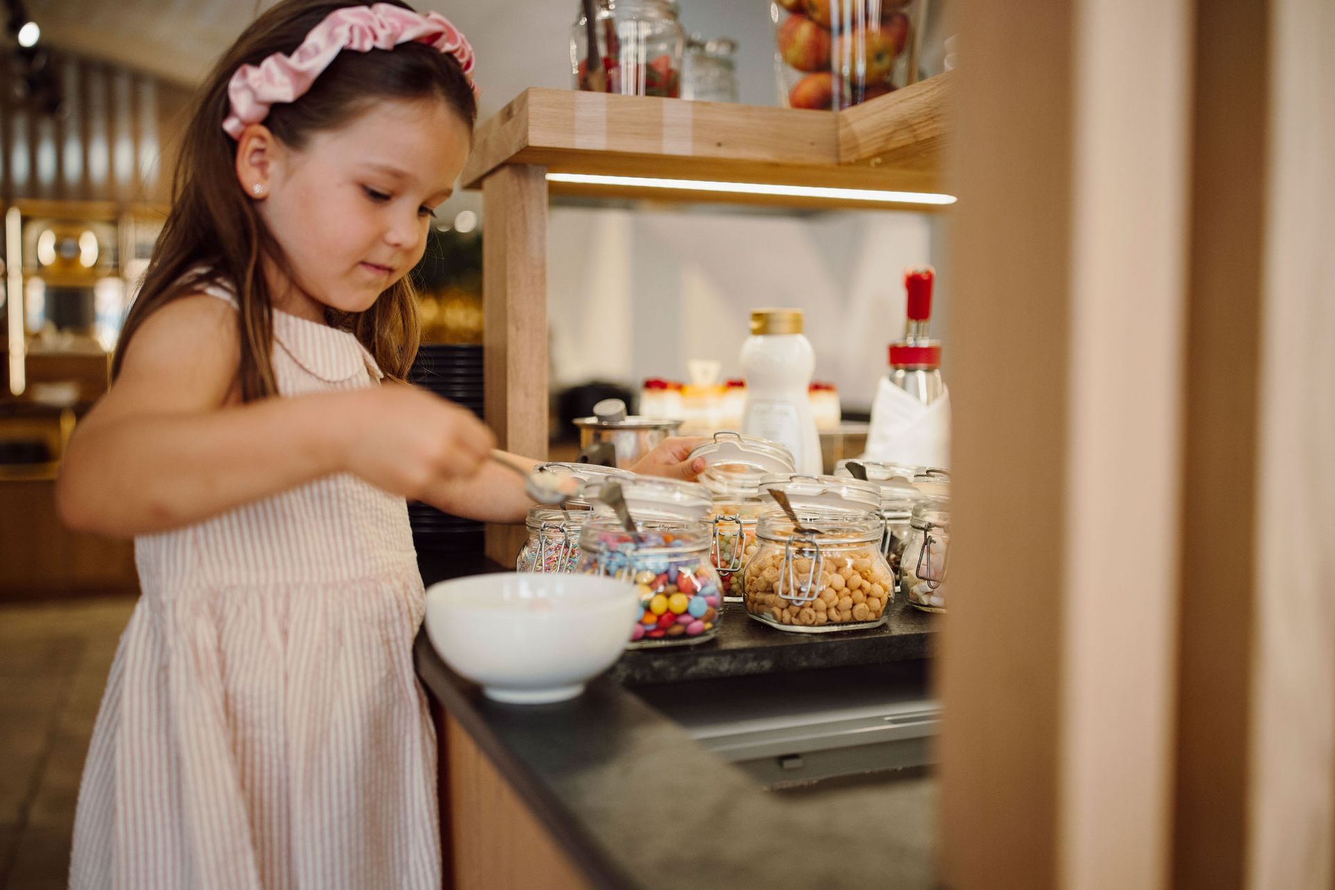 Ein kleines Mädchen legt an einem Buffet Süßigkeiten in eine Schüssel.