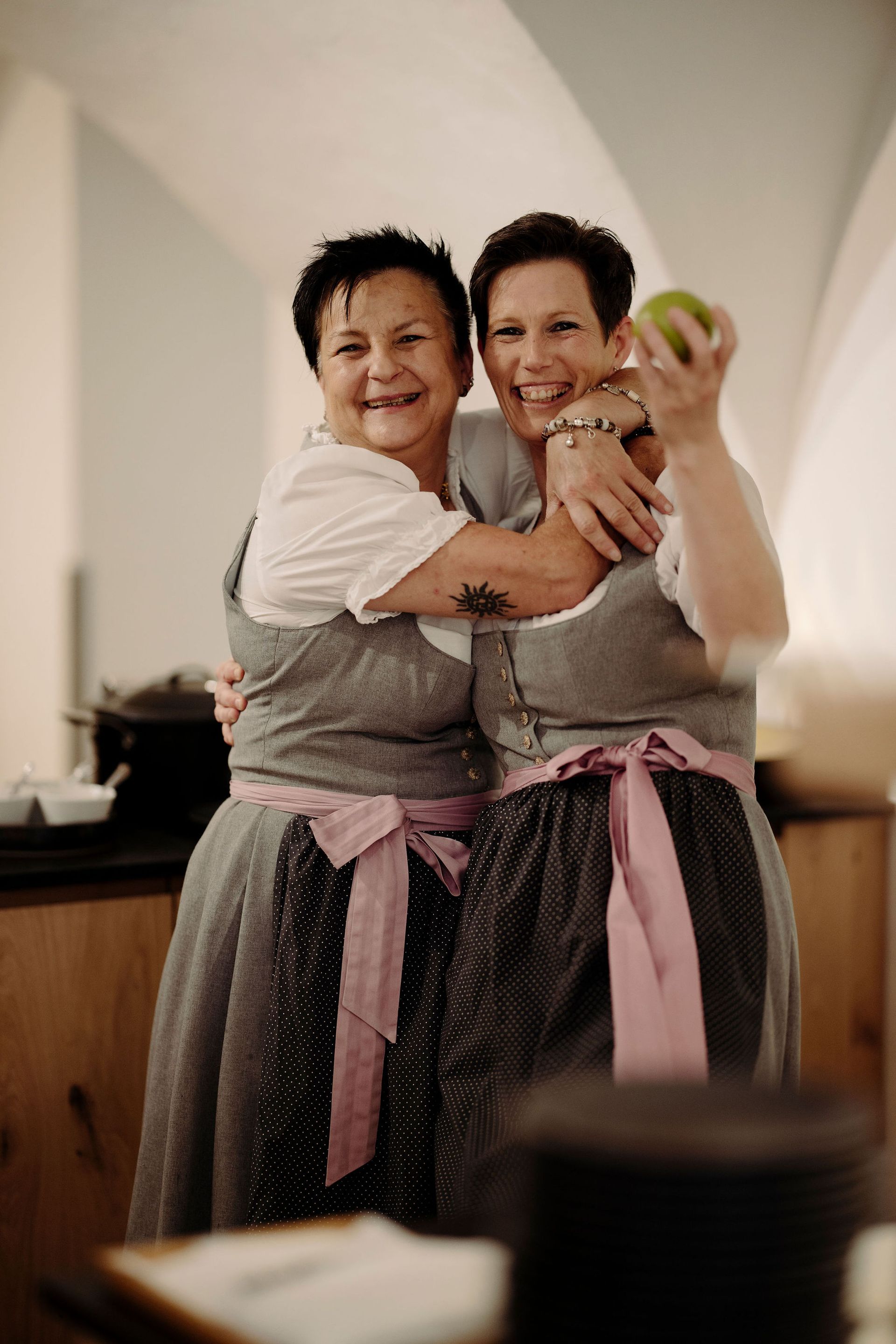 Zwei Frauen umarmen sich und eine hält einen Apfel.