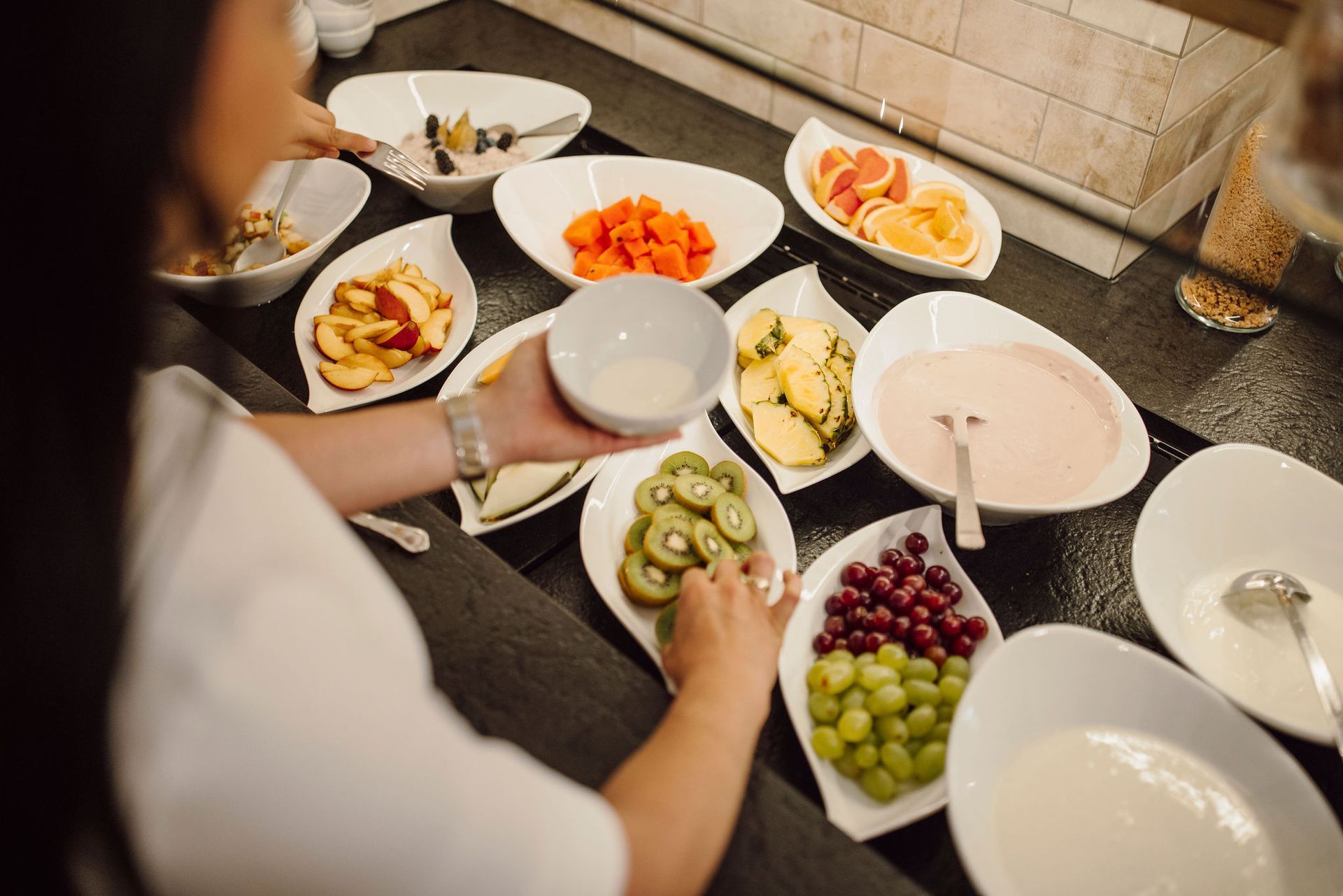 Eine Frau nimmt eine Schale Obst von einem Buffet.