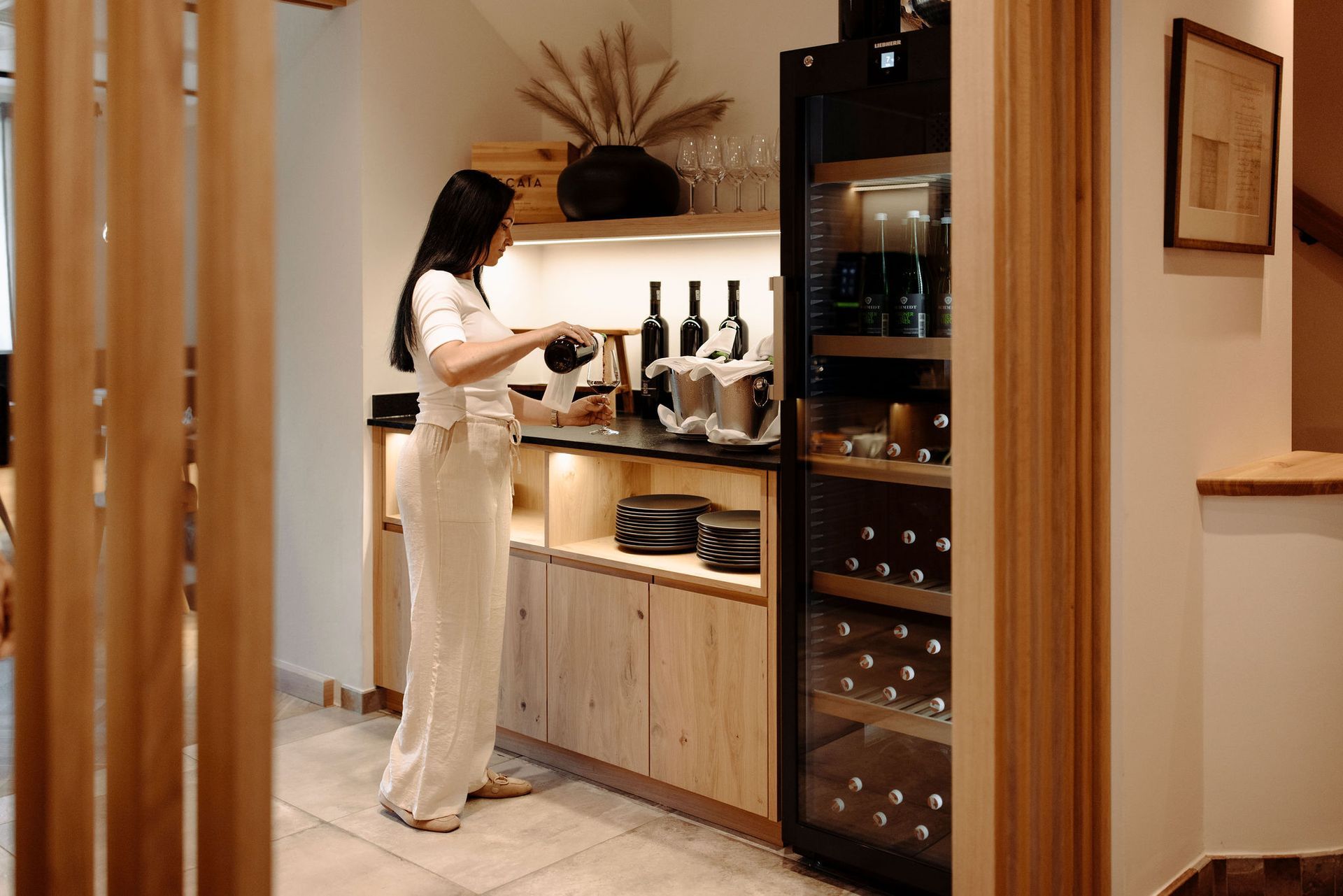 Eine Frau gießt in einer Küche Wein in ein Glas.