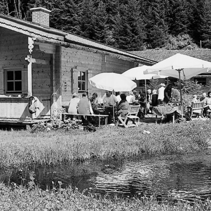 Ein SchwarzweiĂfoto von Leuten, die vor einer HĂźtte sitzen