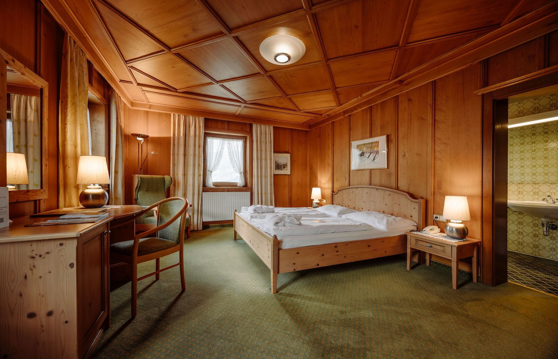 Ein Hotelzimmer mit Bett, Schreibtisch, Stuhl und Spiegel.