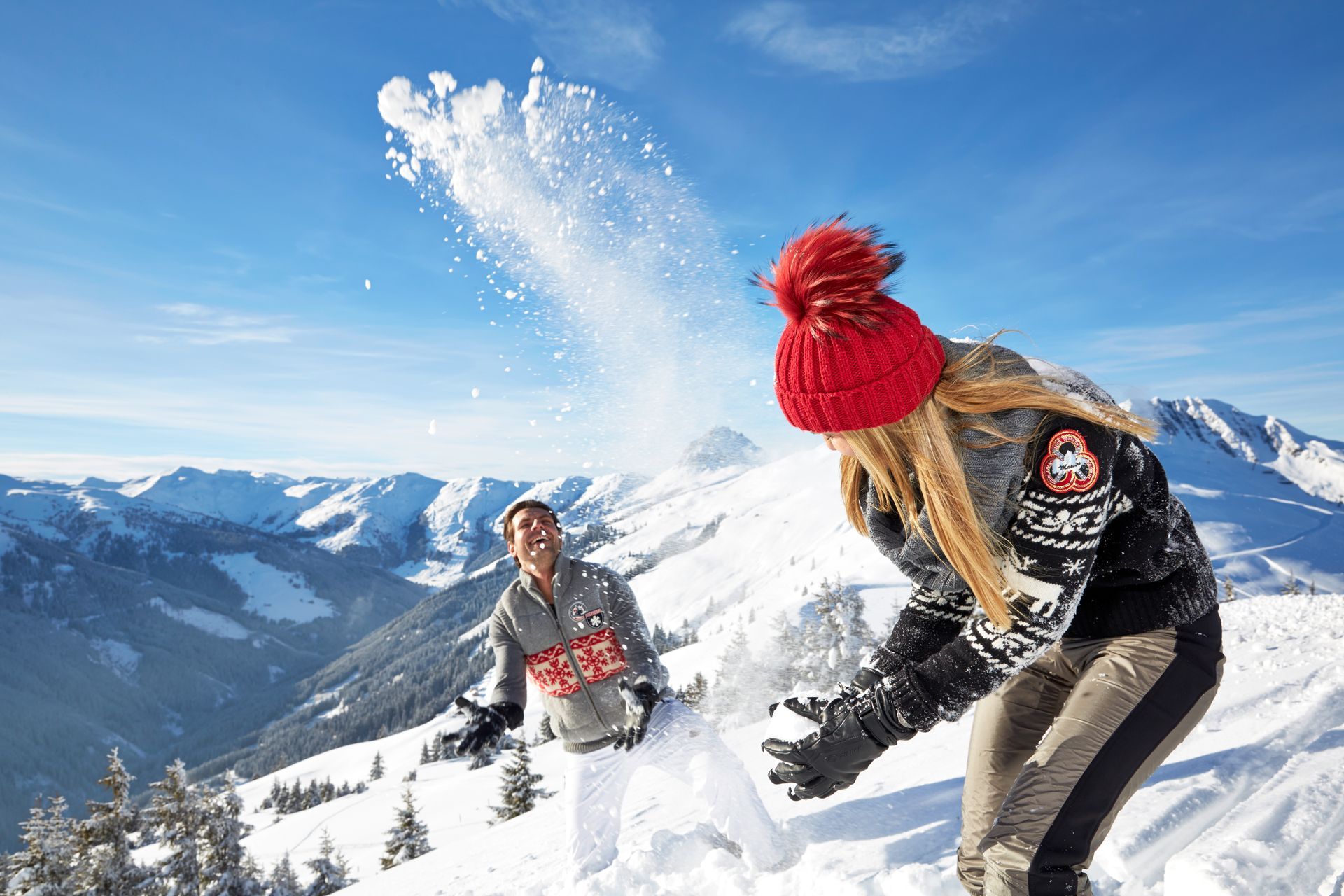 Ein Mann und eine Frau spielen im Schnee auf dem Gipfel eines schneebedeckten Berges.