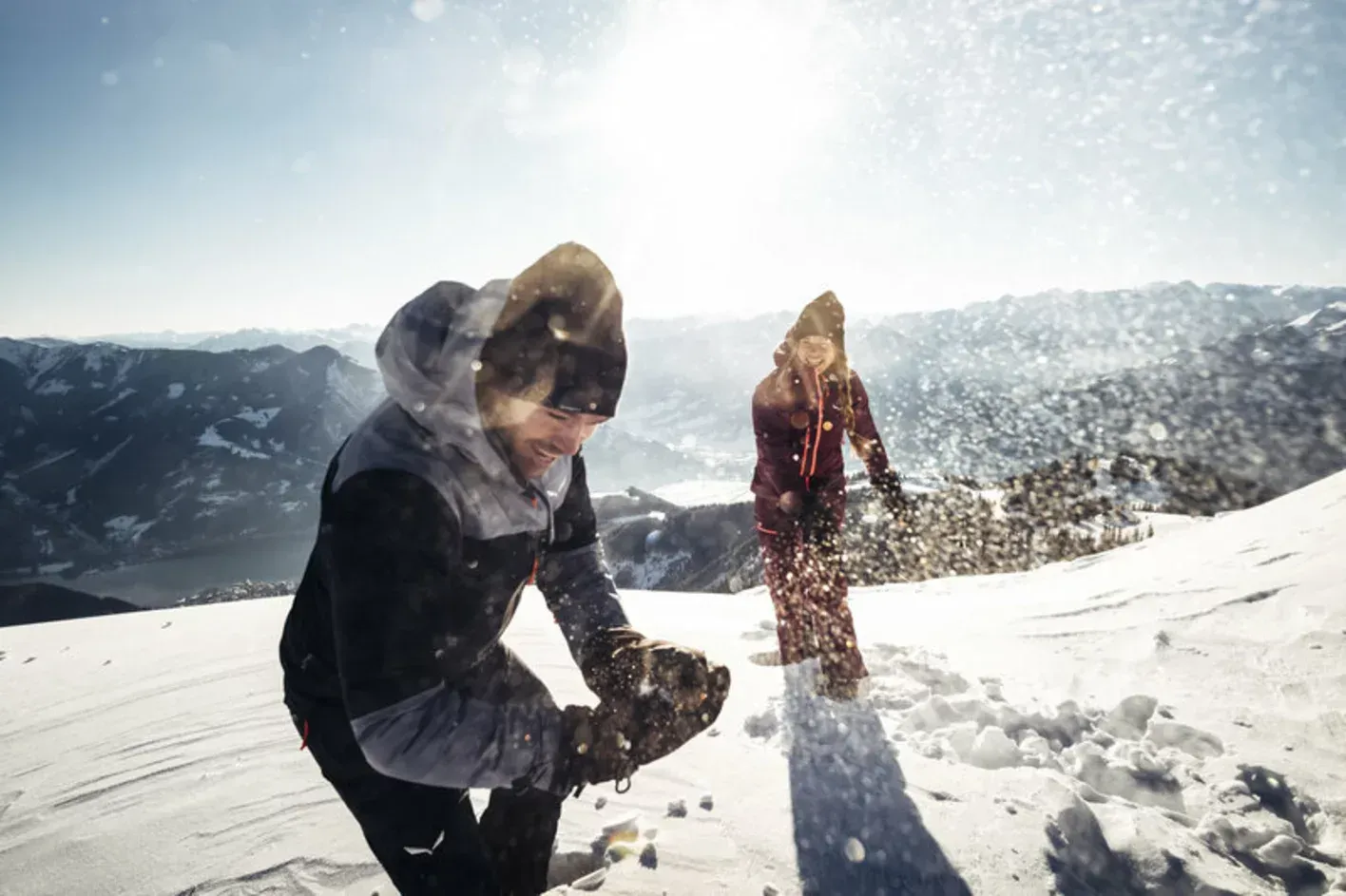 Zwei Leute spielen im Schnee auf dem Gipfel eines schneebedeckten Berges.