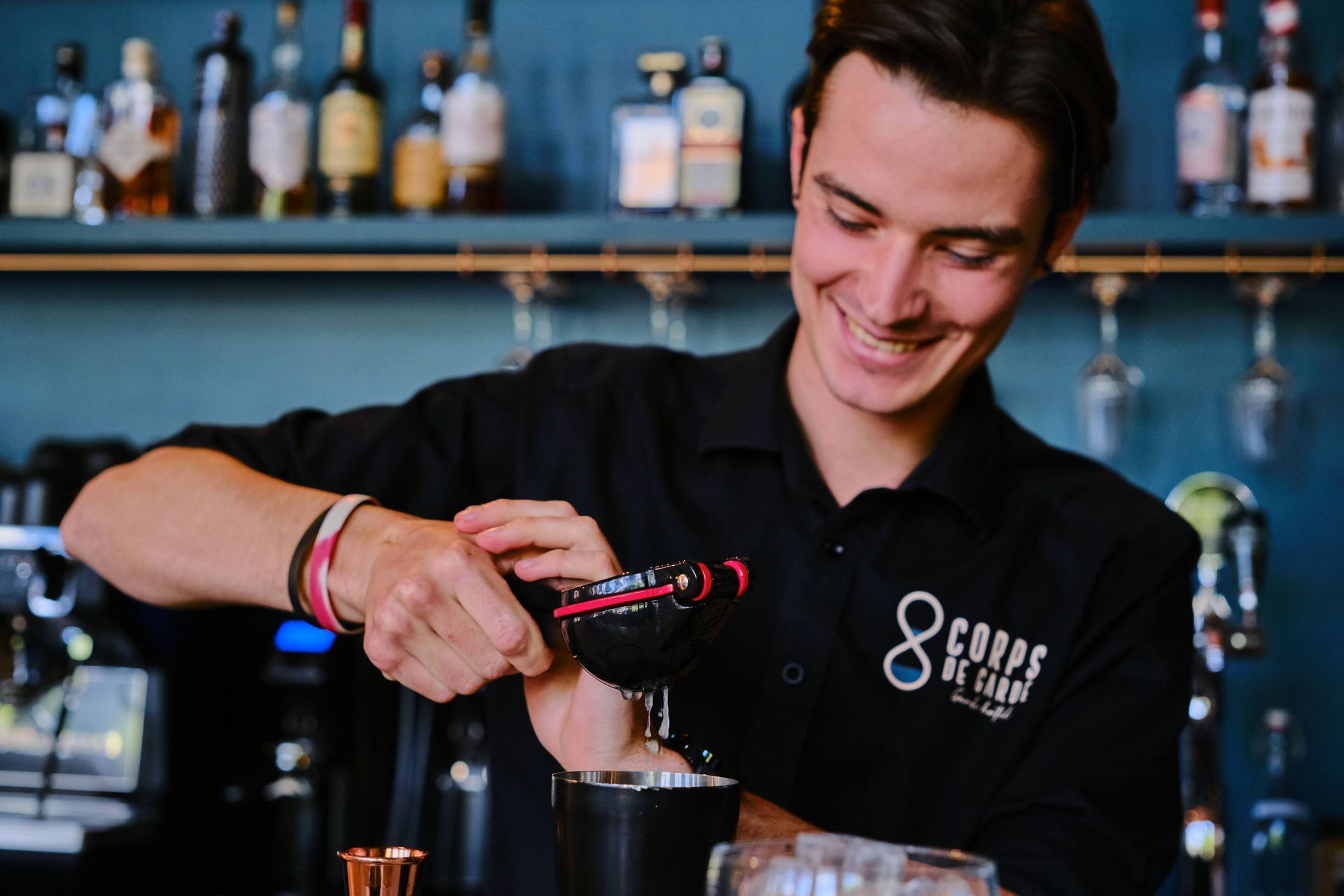 A bartender is smiling while preparing a drink in a bar.