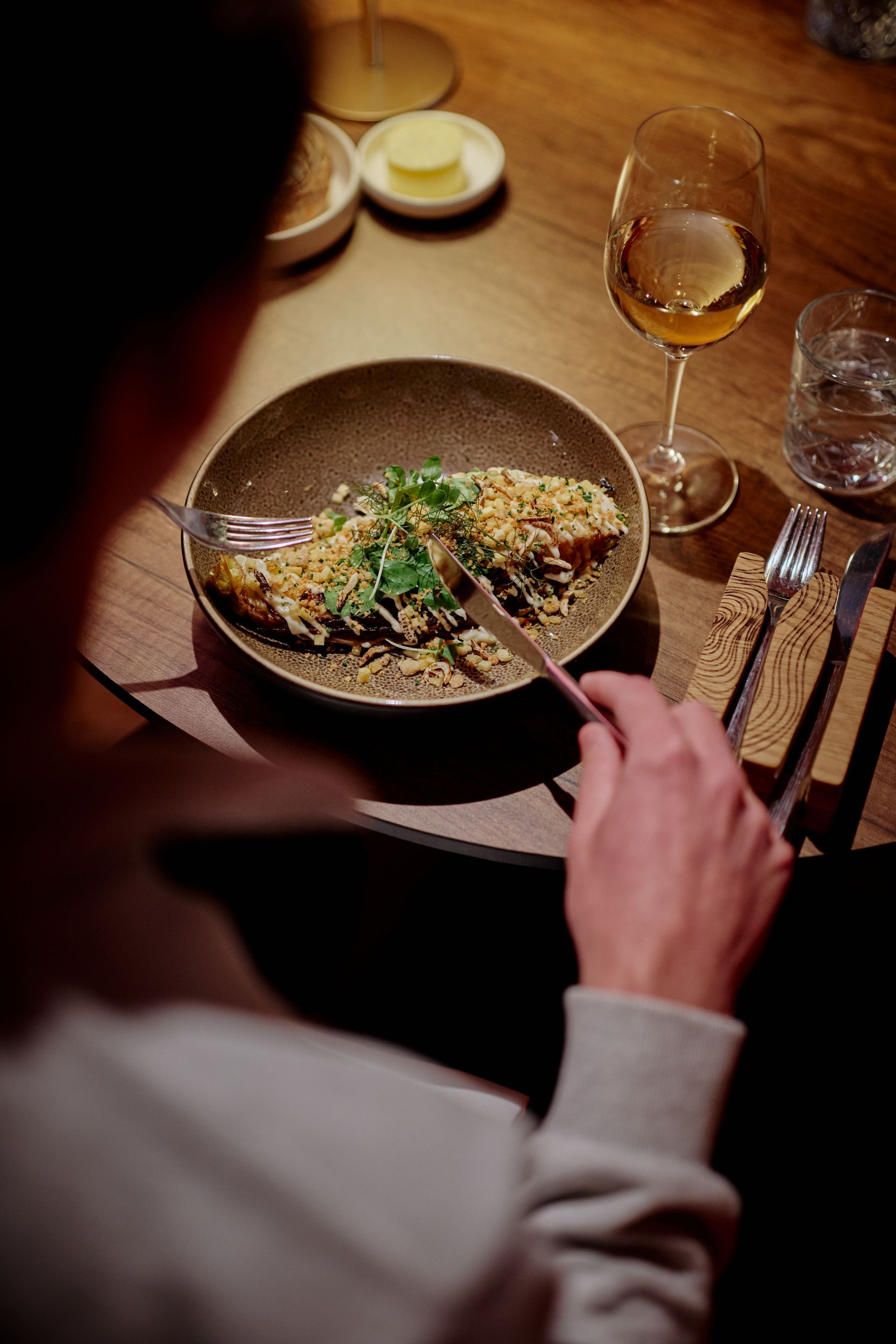 Rood bakstenen gebouw met pilaren en een donker dak, met een vlag in de lucht, in een zonnige straat in een Europese stad.
