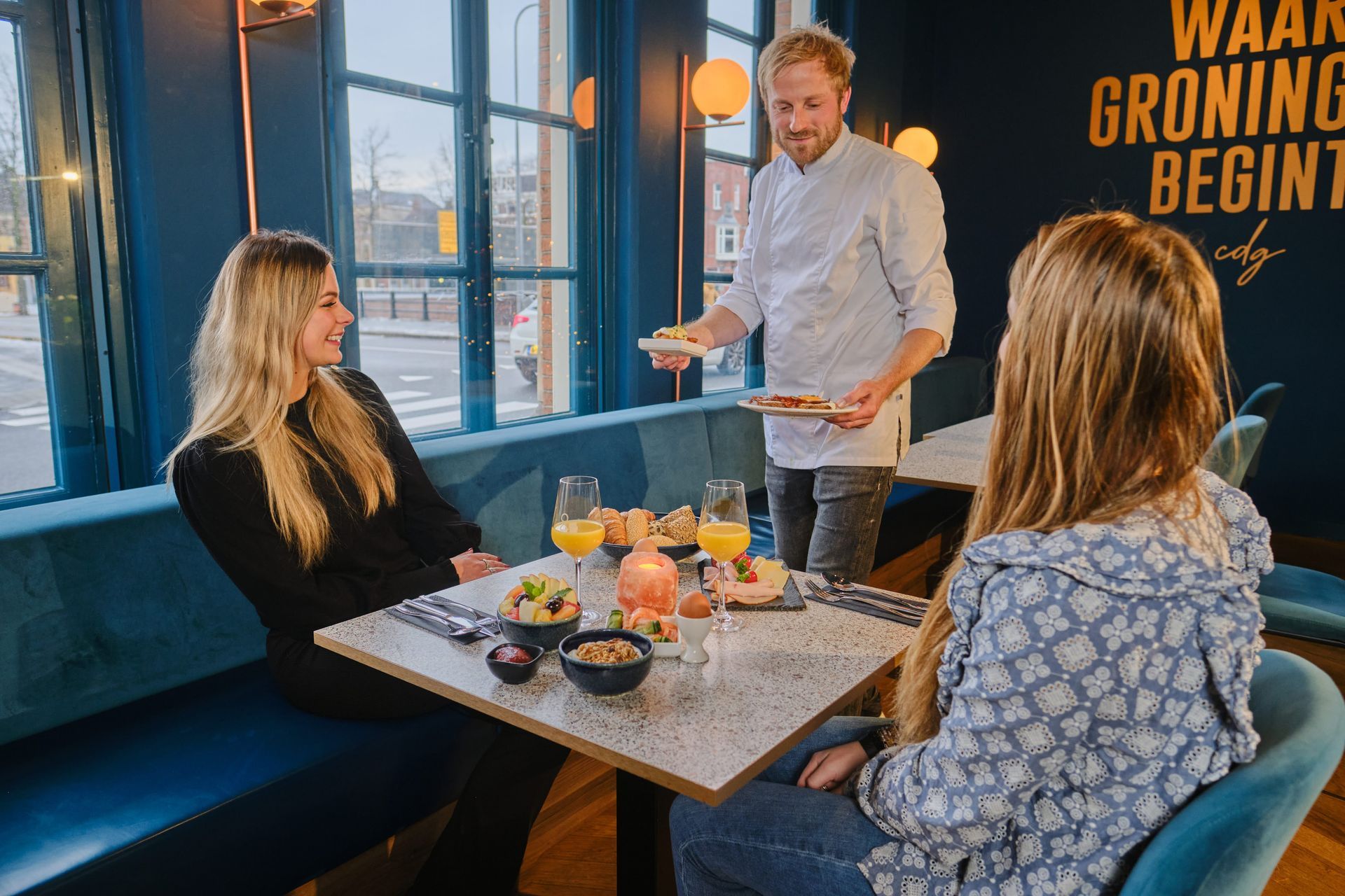 Ein Mann serviert zwei Frauen an einem Tisch in einem Restaurant Essen.