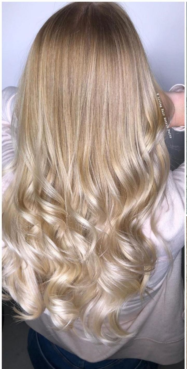 Eine Frau mit langen blonden Haaren trägt ein weißes Hemd und blaue Jeans.