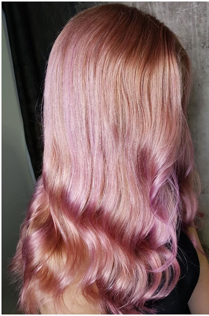 Eine Frau mit langen rosa Haaren trägt ein schwarzes Hemd.