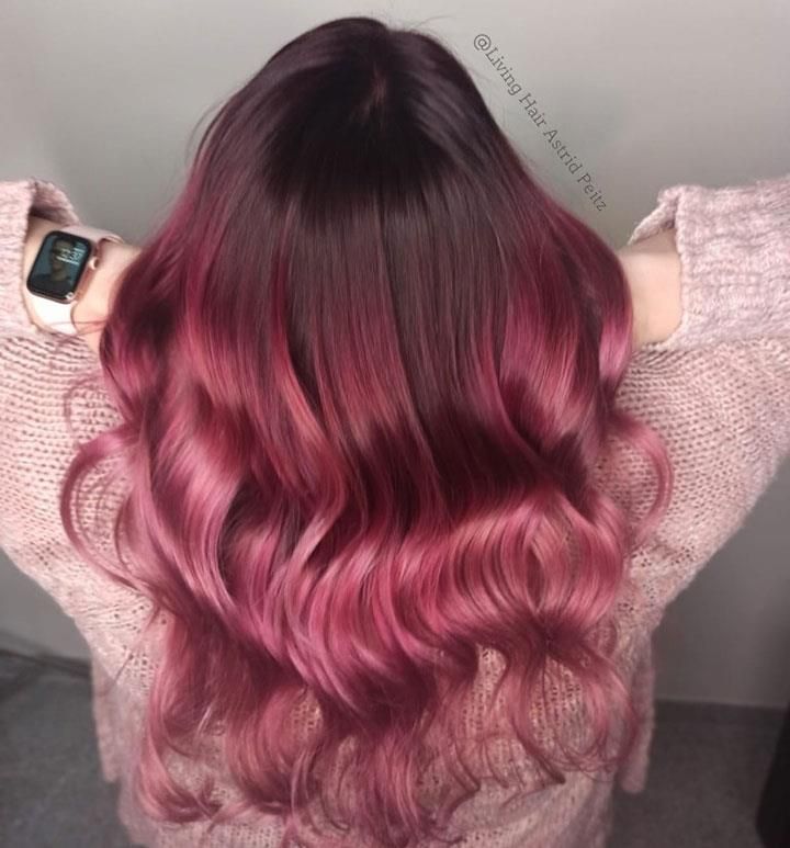 Eine Frau mit langen rosa Haaren trägt einen rosa Pullover und eine Uhr.