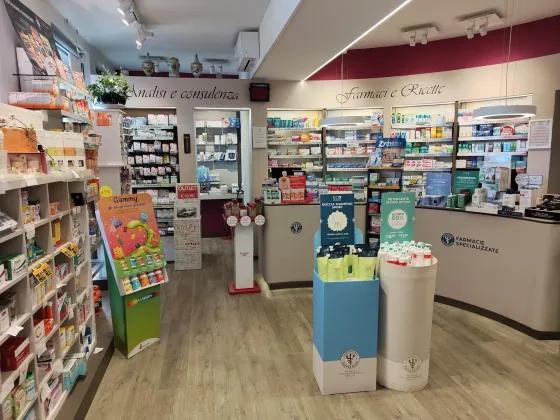 Una farmacista bionda in camice bianco prende i farmaci da uno scaffale in una farmacia ben illuminata.