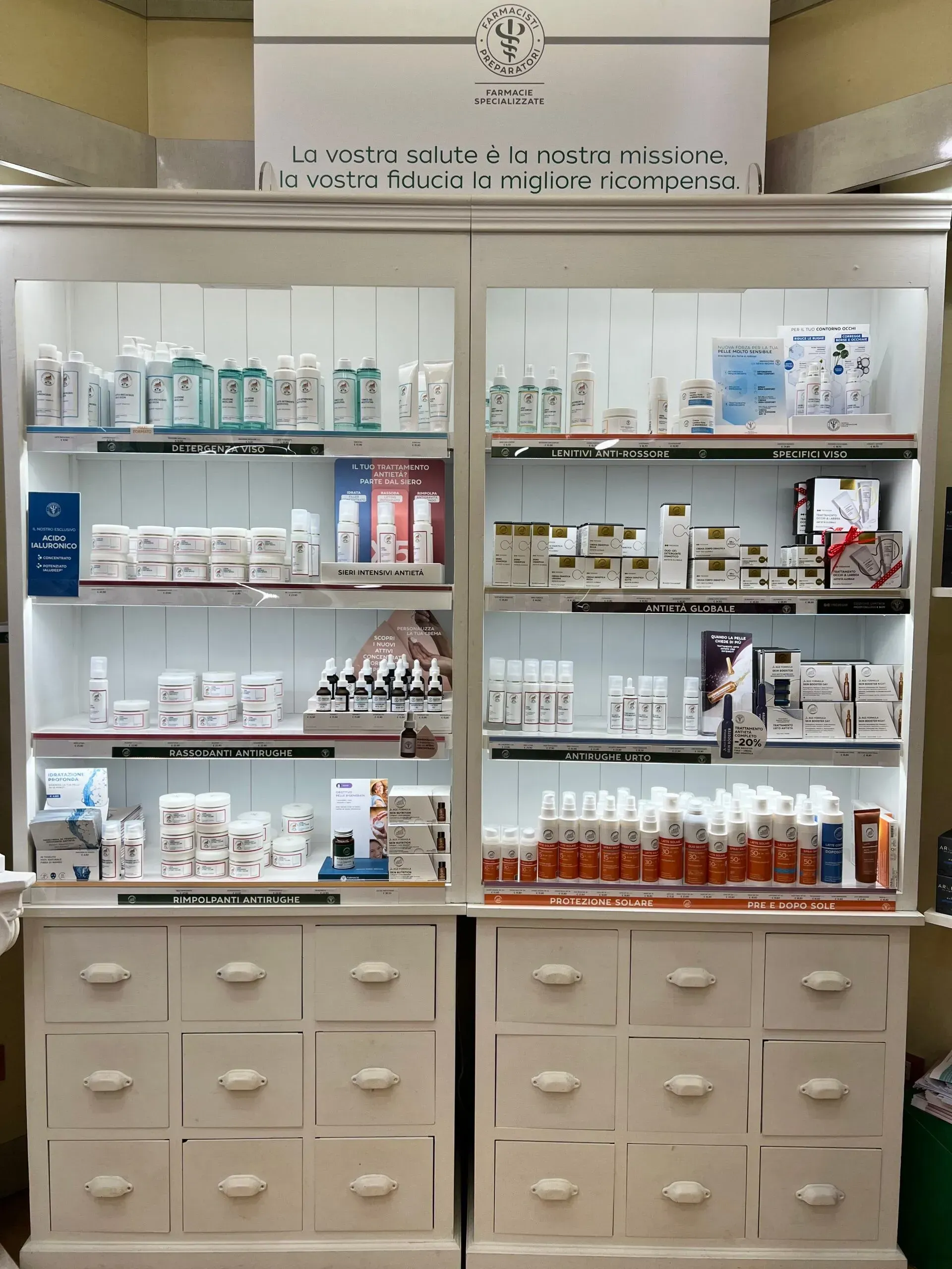 Scaffali bianchi in una farmacia, con prodotti per la cura della pelle e medicinali, in un negozio luminoso e ben organizzato.
