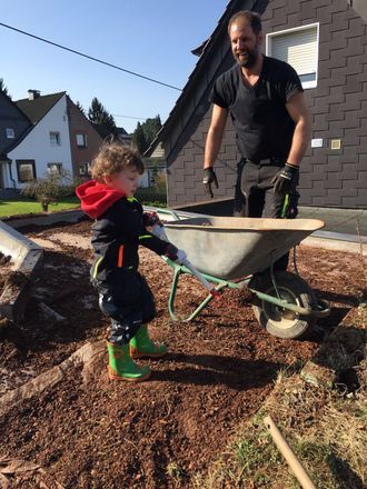 Kleiner Junge hilft mit seiner Schippe bei Dachdeckerarbeit