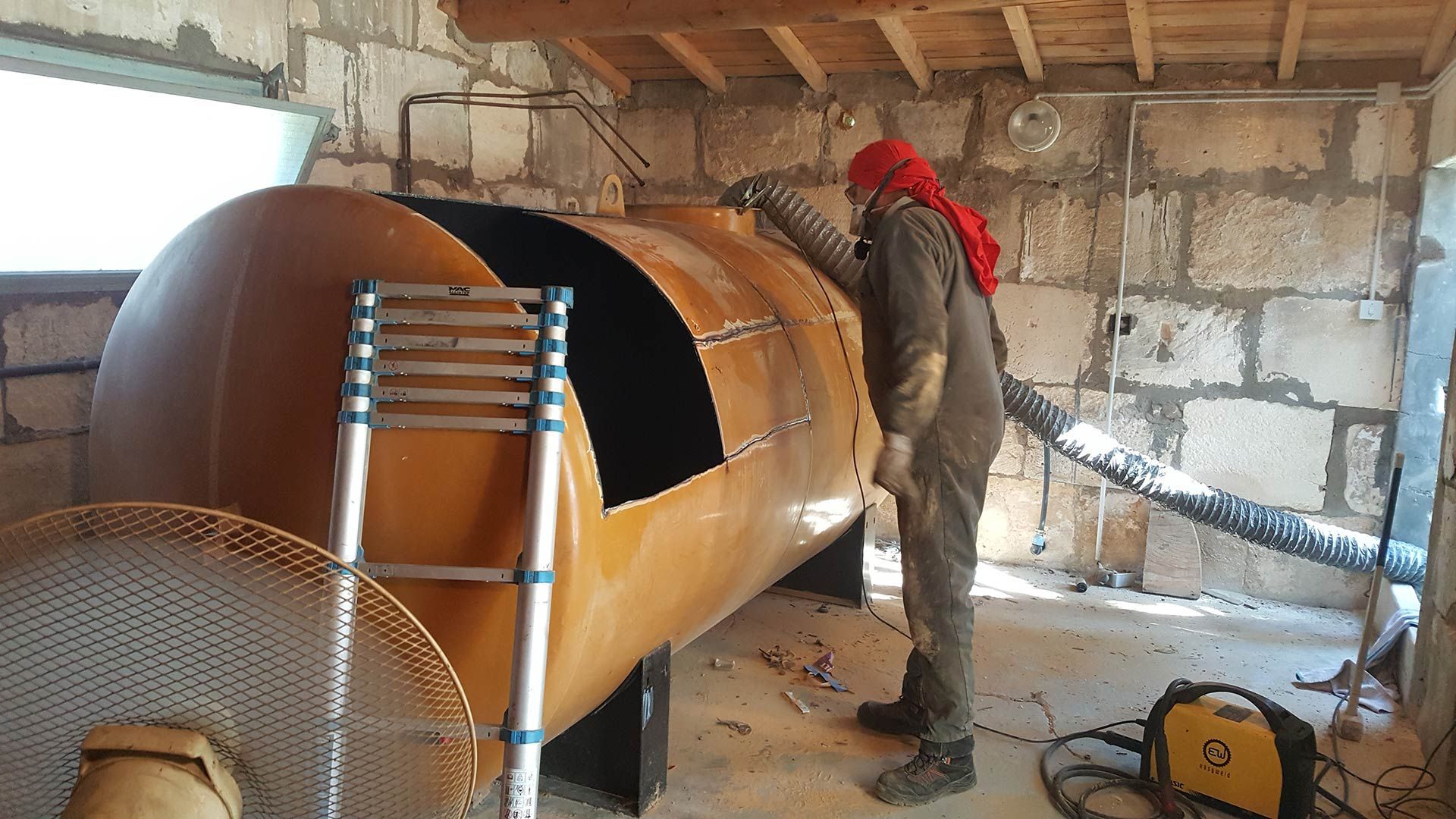 Une personne nettoyant un réservoir à fioul.