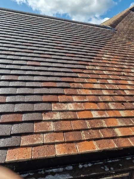 Weathered red-brown tiled roof under a partly cloudy sky